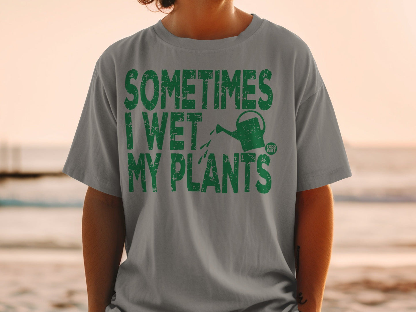 Gray t-shirt with green text: "Sometimes I Wet My Plants" and a watering can icon.