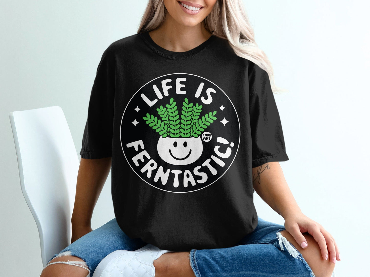 Black t-shirt with "LIFE IS FERNTASITC!" text and a smiling potted plant.