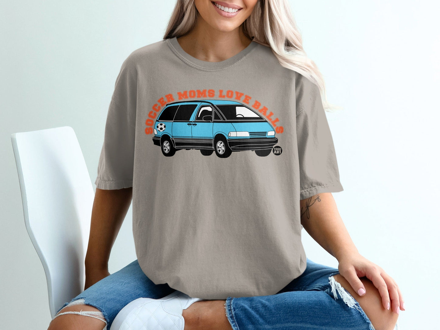 Light brown t-shirt with blue van and orange text "Soccer Moms Love Balls".