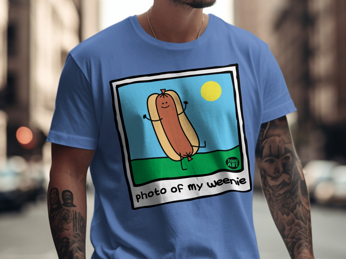 Blue t-shirt with illustration of a happy hot dog in a bun, "photo of my weenie" text.