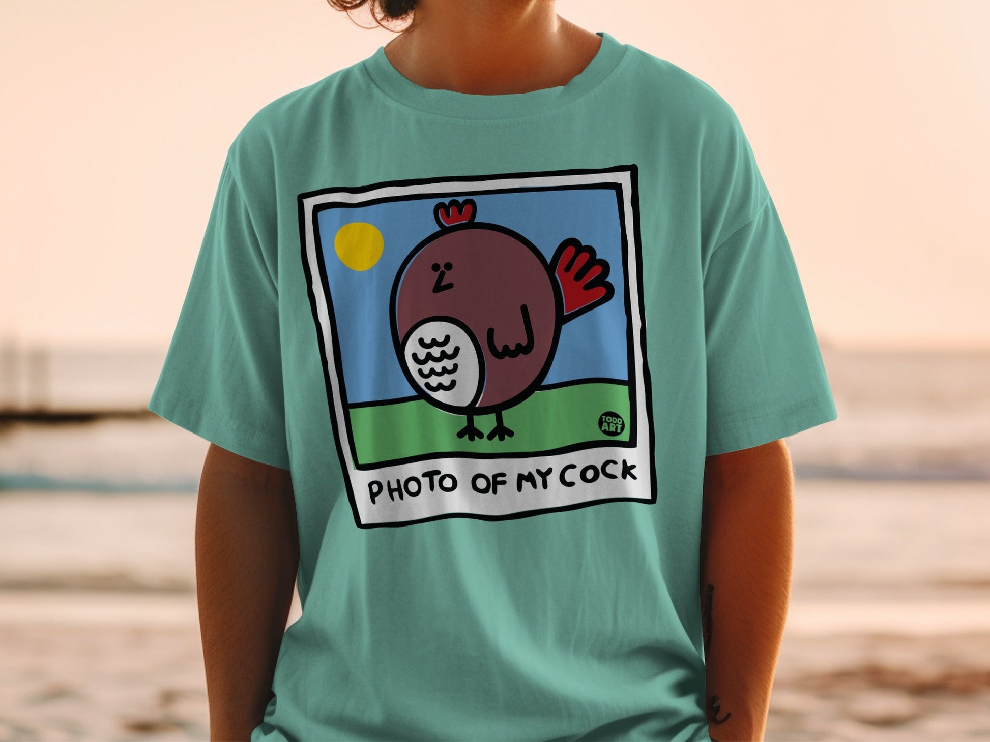 Teal t-shirt with graphic of a brown bird with red comb and "PHOTO OF MY COCK" text.
