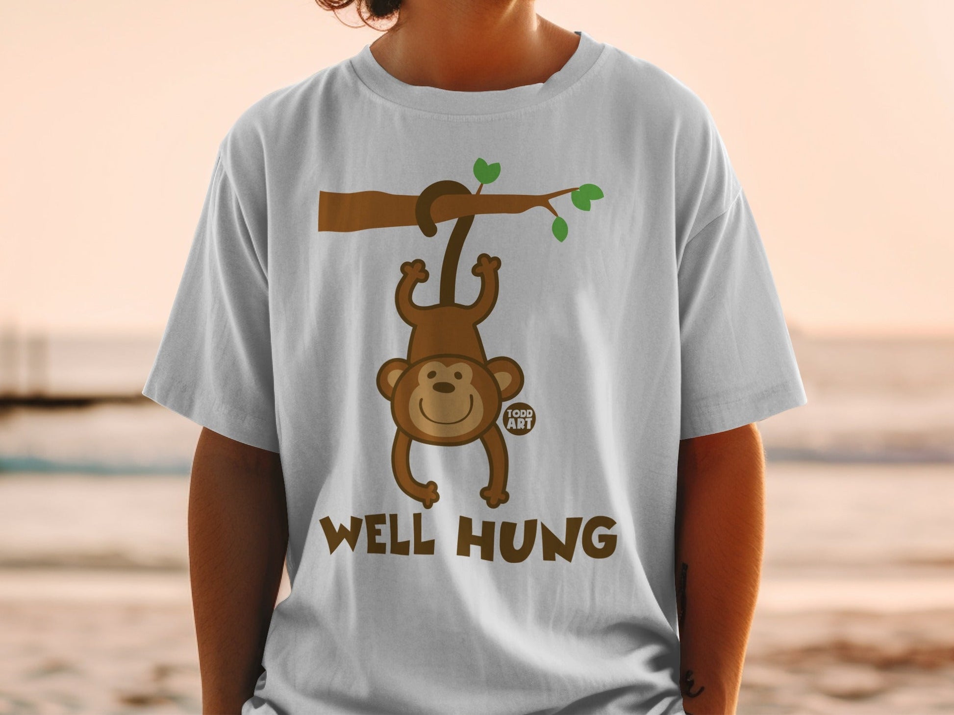 White t-shirt with a cartoon monkey hanging from a branch, saying "WELL HUNG".
