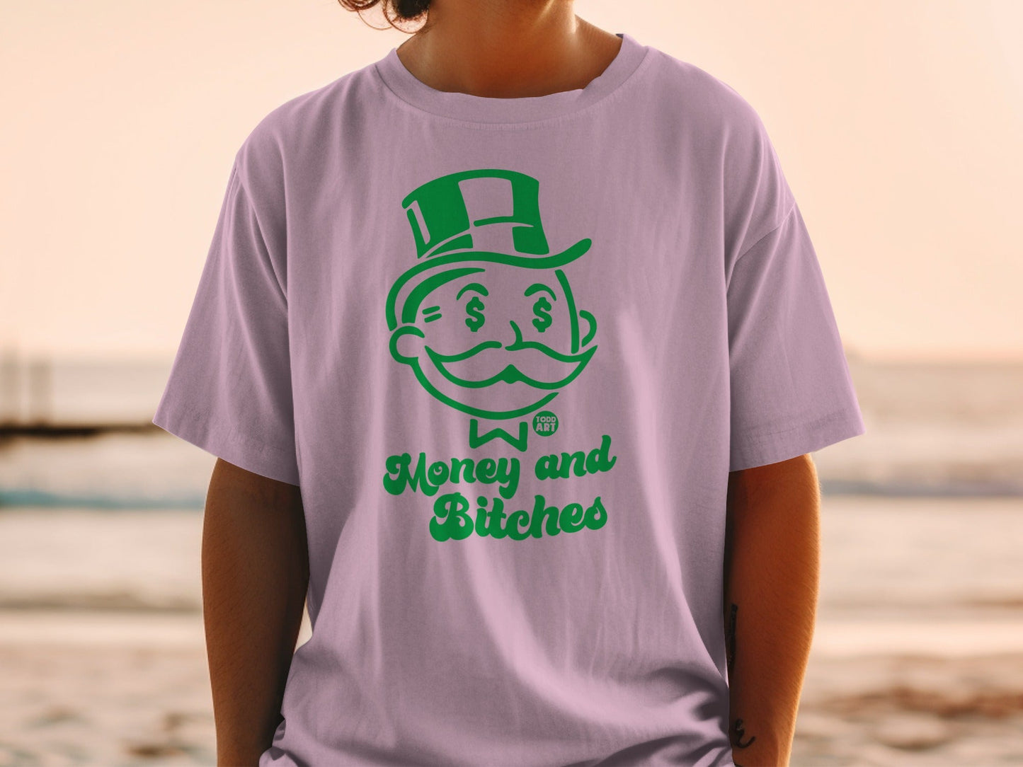 Green Monopoly Man graphic on a light purple t-shirt with "Money and Bitches" text.