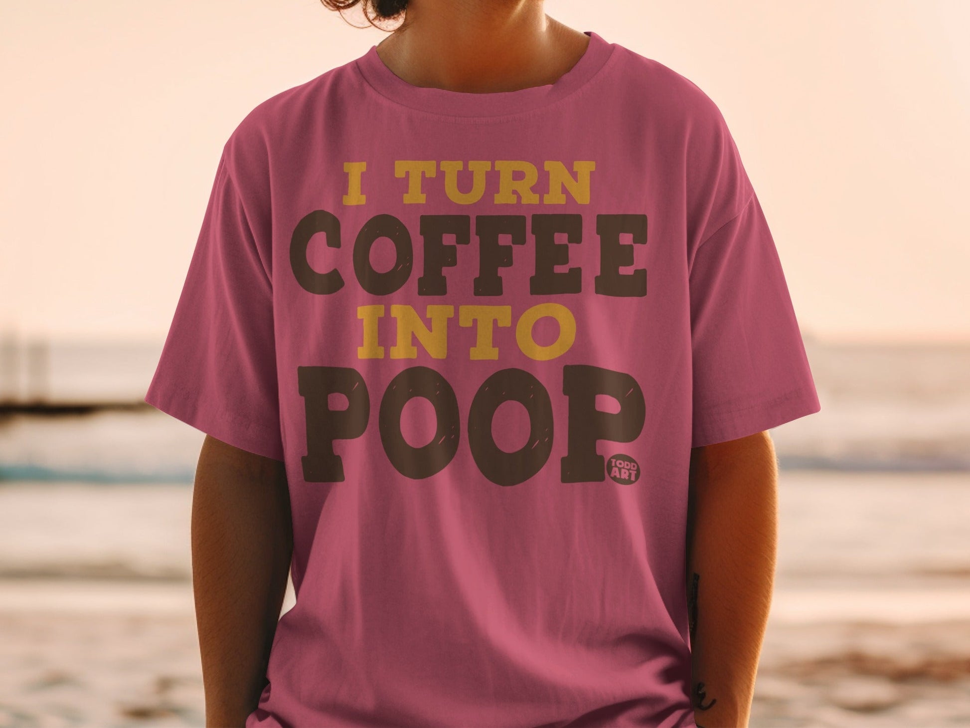 Pink t-shirt with yellow text that reads "I turn coffee into poop".