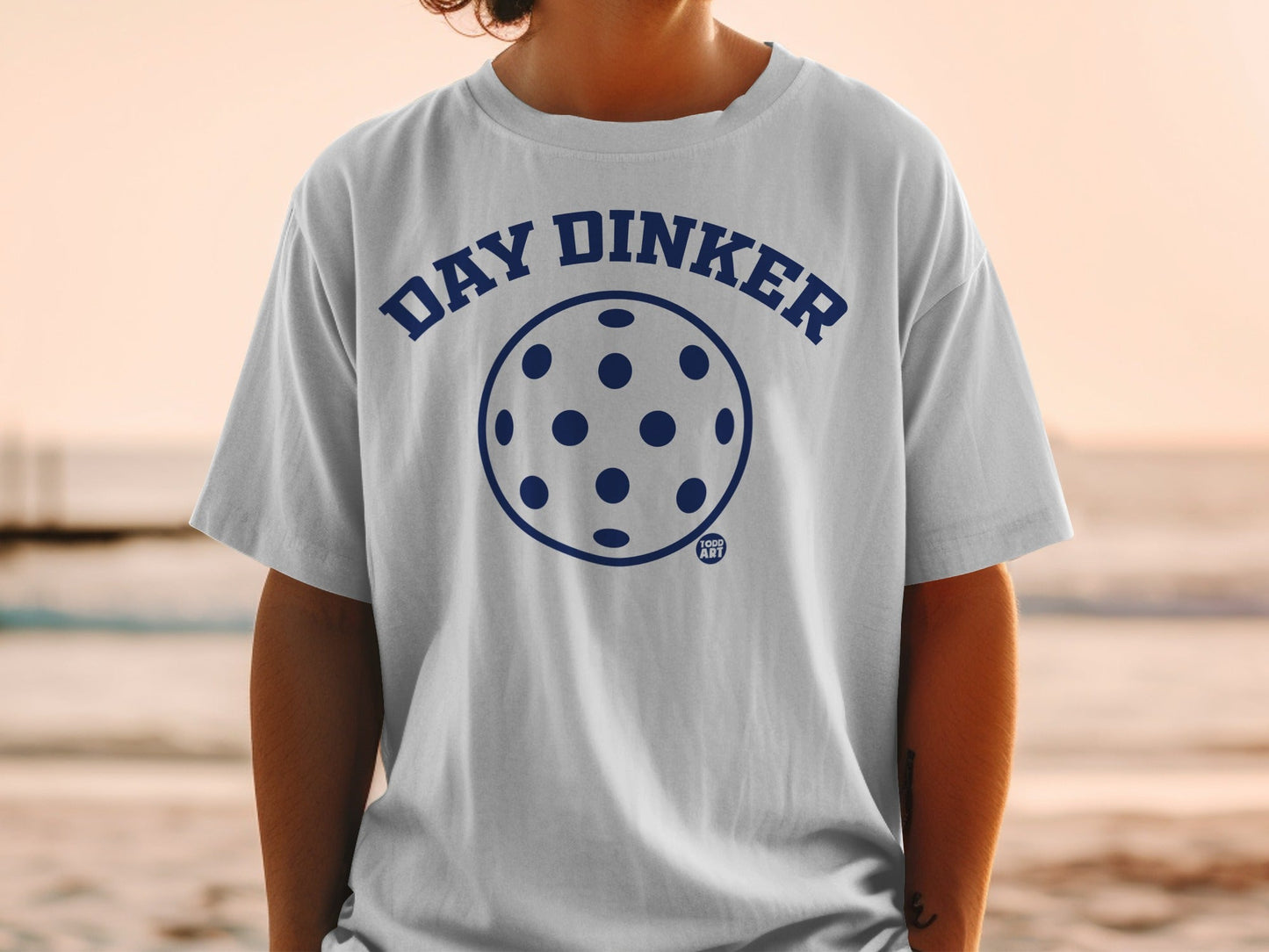 White t-shirt with navy blue "DAY DINKER" pickleball graphic.