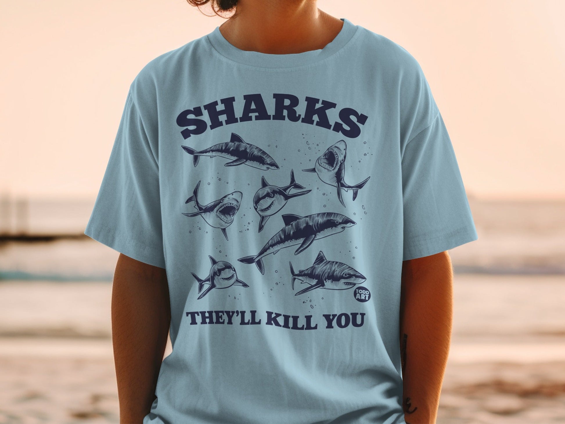 Light blue t-shirt with sharks and text "SHARKS THEY'LL KILL YOU".