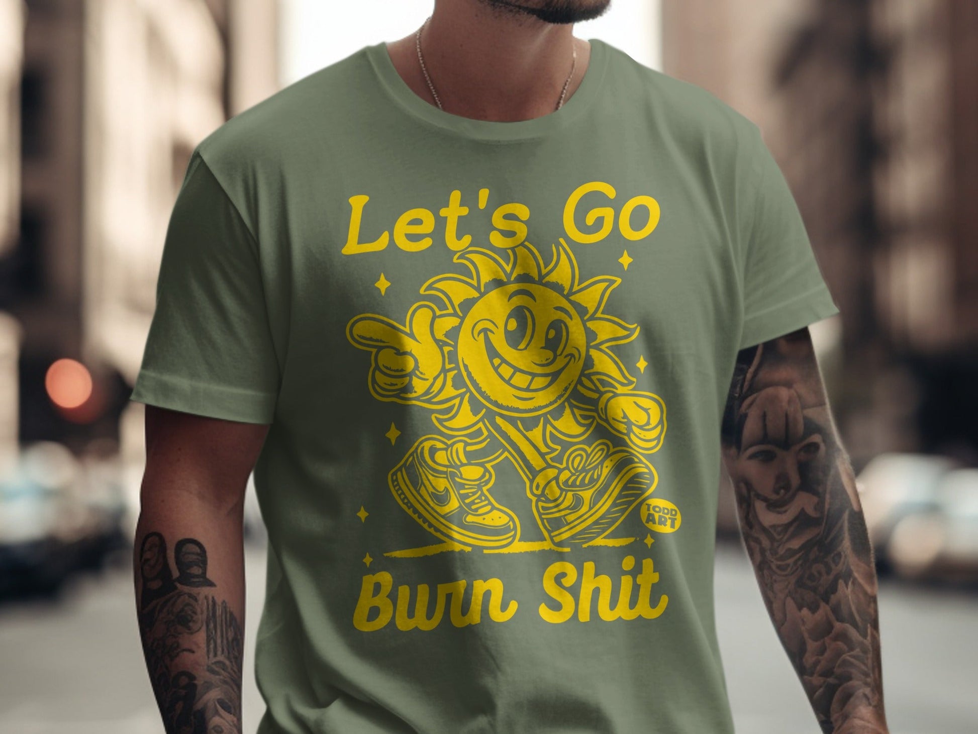 Green t-shirt with yellow "Let's Go Burn Shit" text and cartoon sun graphic.