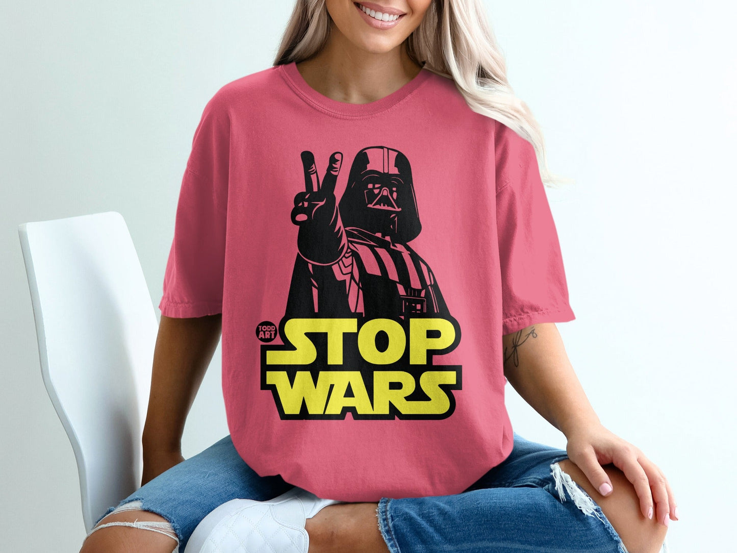 Darth Vader giving a peace sign on a pink t-shirt with "1000 ART" and "STOP WARS" text.