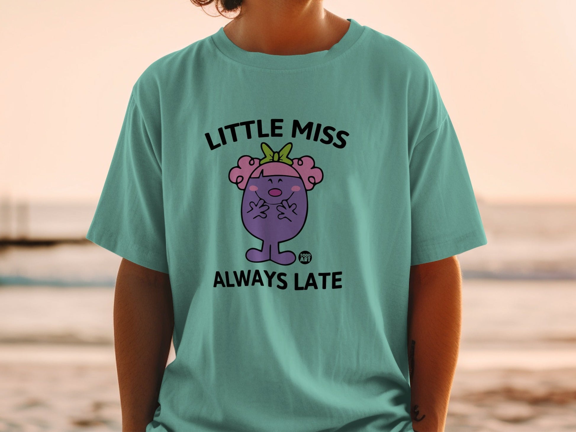 Teal t-shirt with "Little Miss Always Late" cartoon character graphic.