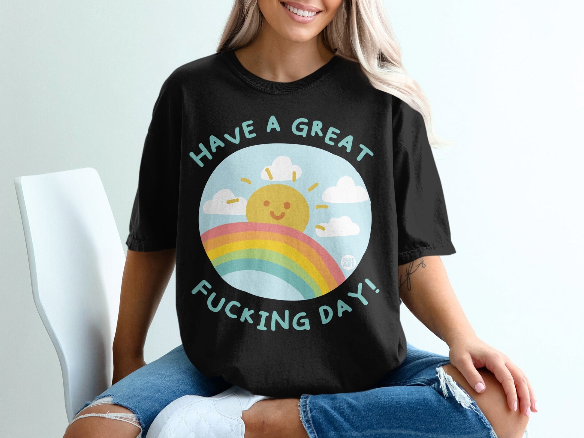 Black t-shirt with a sun, rainbow, and text "Have a great fucking day!".