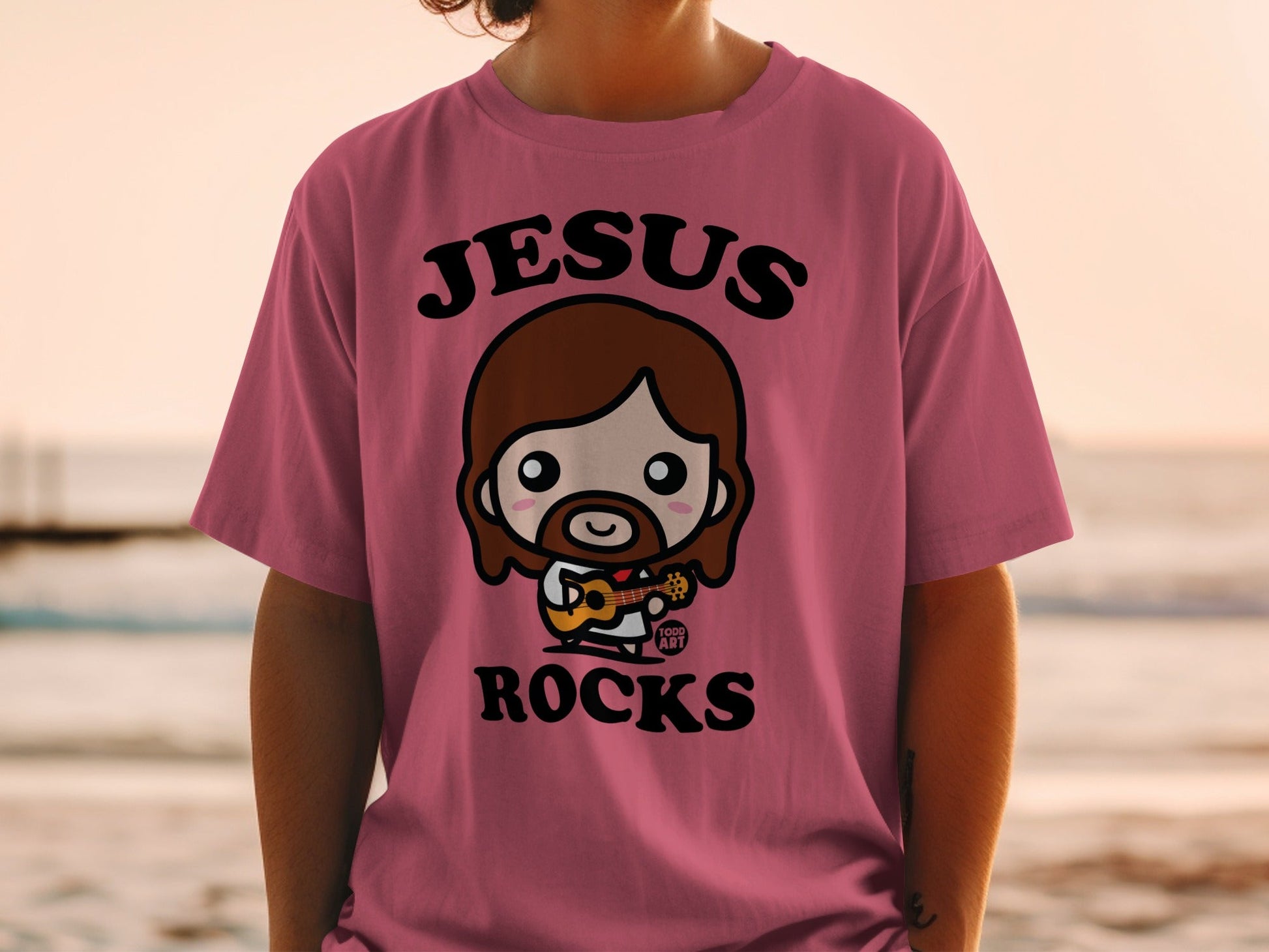 Chibi Jesus graphic on a pink t-shirt, "Jesus Rocks" text.