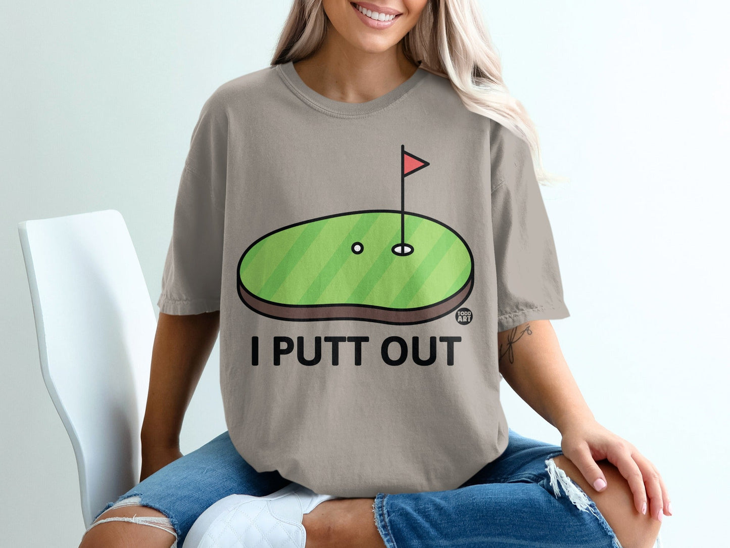 T-shirt with a cartoon golf green and "I PUTT OUT" text.