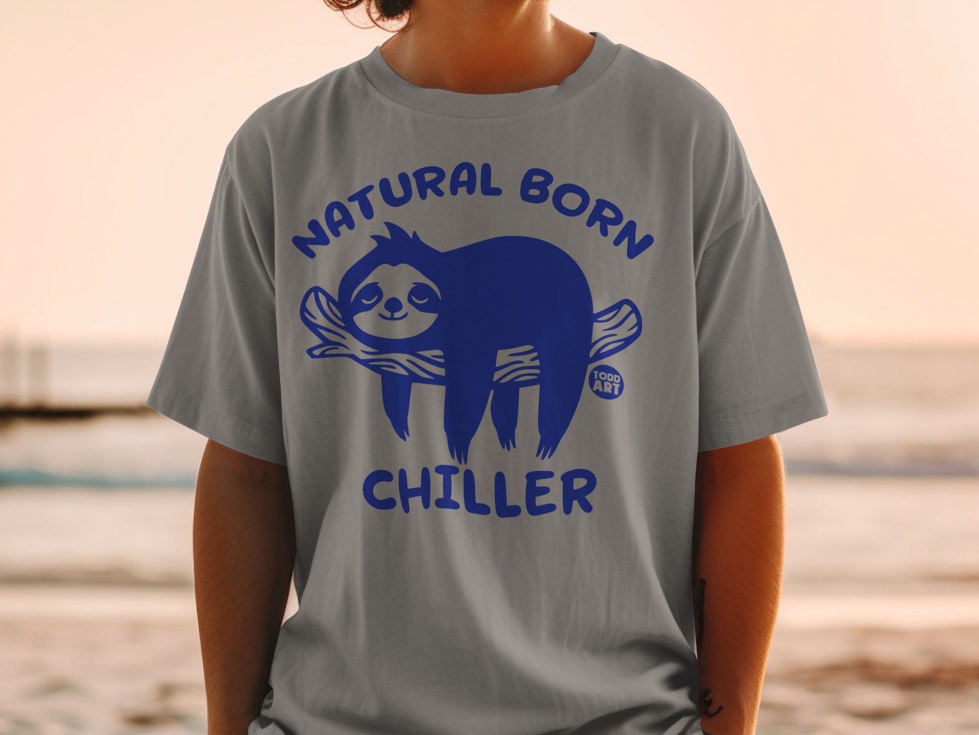 Gray t-shirt with blue graphic of a sloth on a branch saying "Natural Born Chiller".
