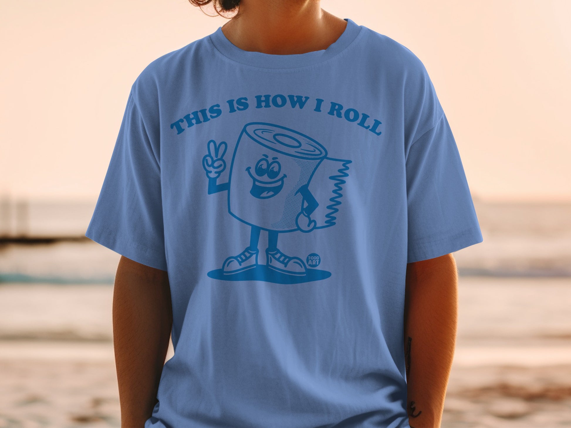 Blue t-shirt with cartoon toilet paper roll giving a peace sign.