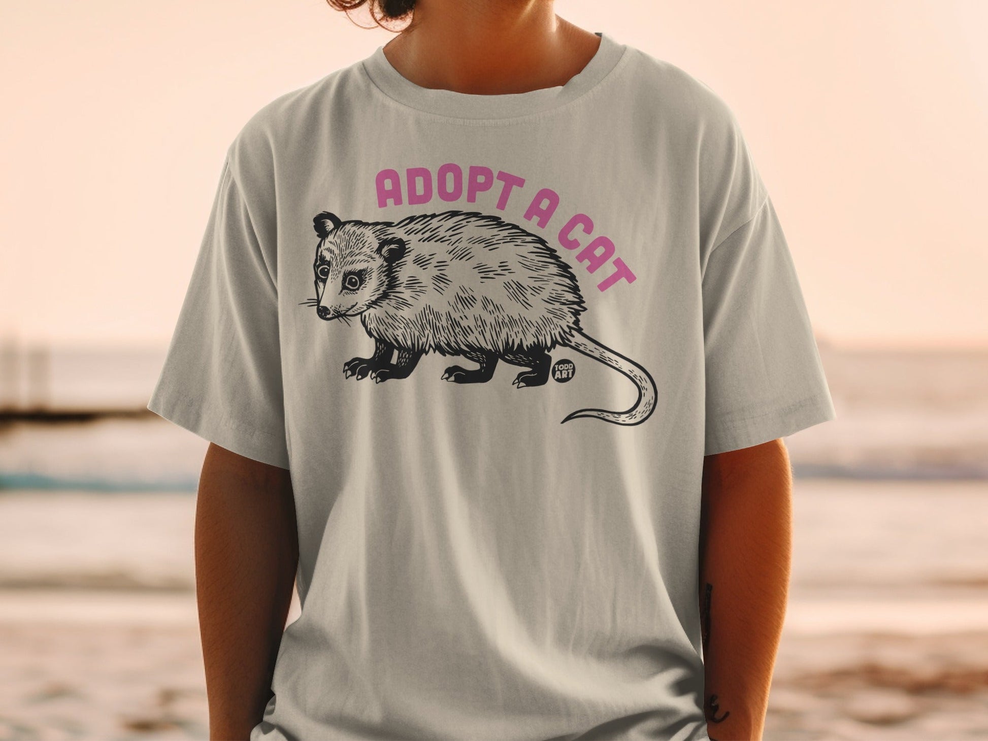 T-shirt with a possum illustration and "ADOPT A CAT" text.