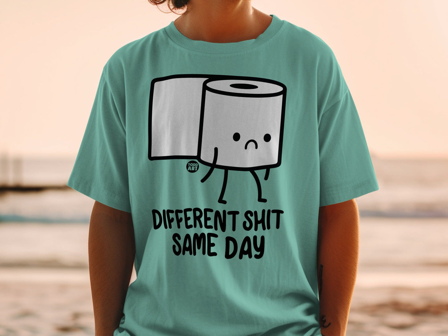 Teal t-shirt with cartoon toilet paper and text "DIFFERENT SHIT SAME DAY".