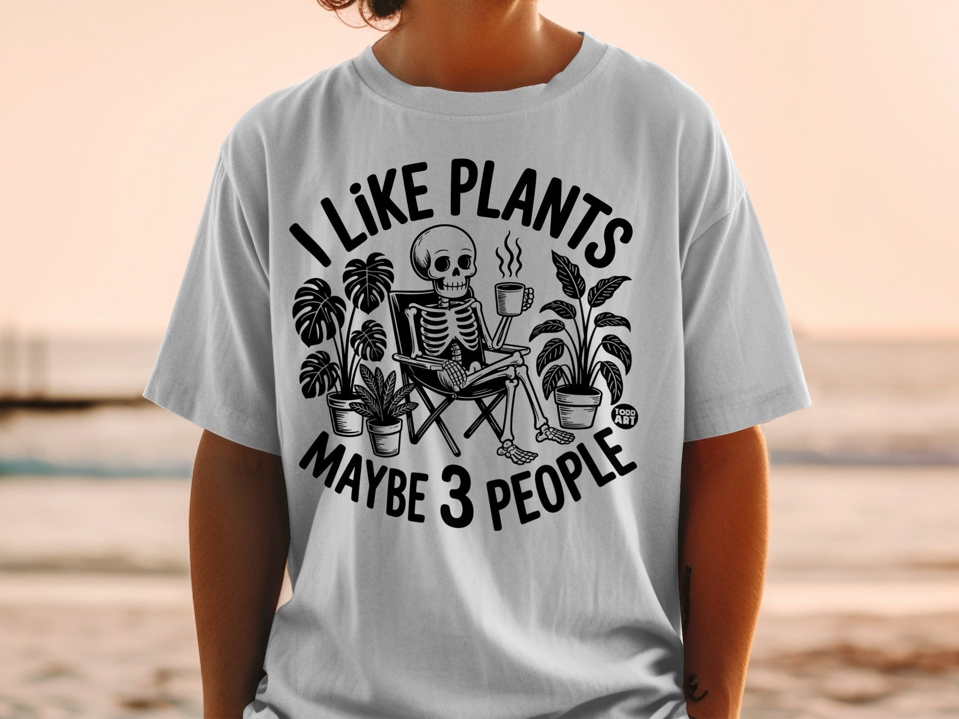 Skeleton sitting in a chair holding a coffee mug, text reads "I LIKE PLANTS MAYBE 3 PEOPLE".