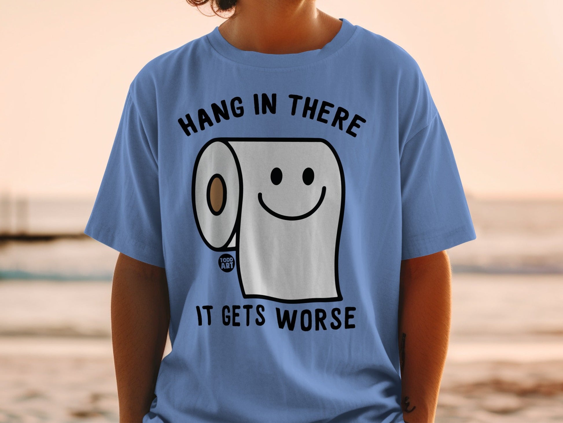 Blue t-shirt with a cartoon toilet paper roll smiling and text.