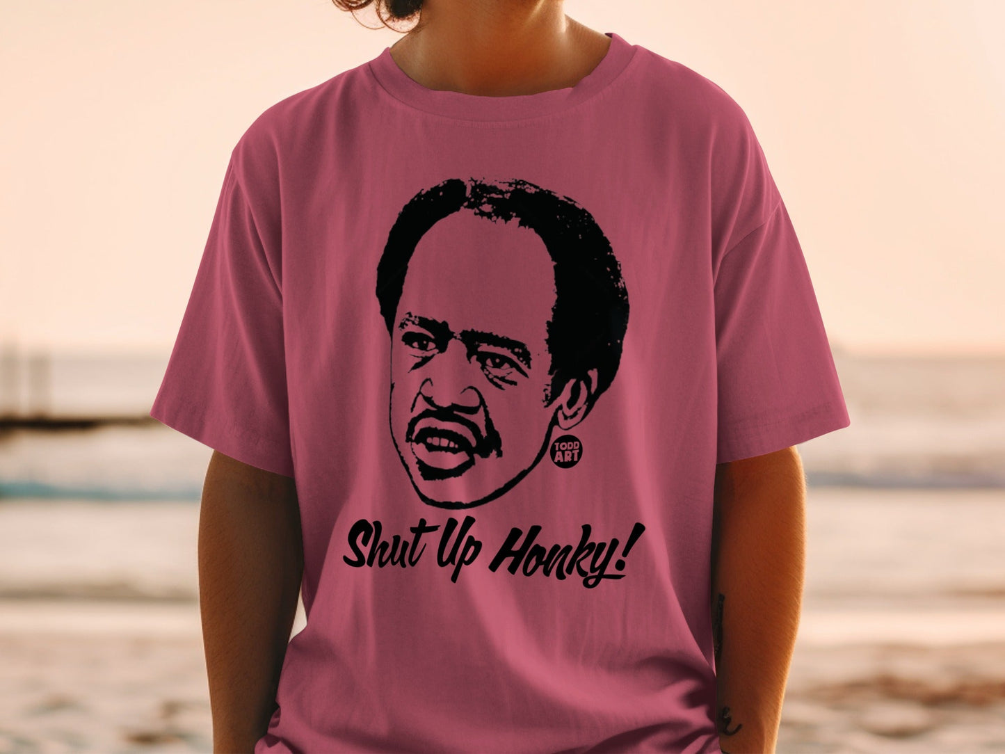 Man wearing pink t-shirt with cartoon portrait and "Shut Up Honky!" text.
