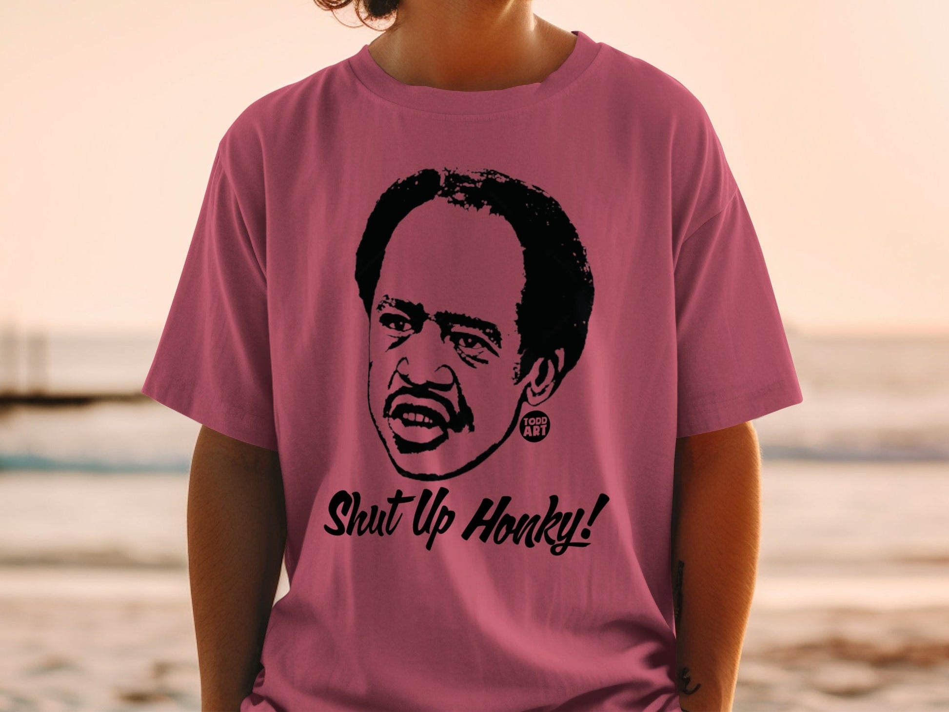Man wearing pink t-shirt with cartoon portrait and "Shut Up Honky!" text.