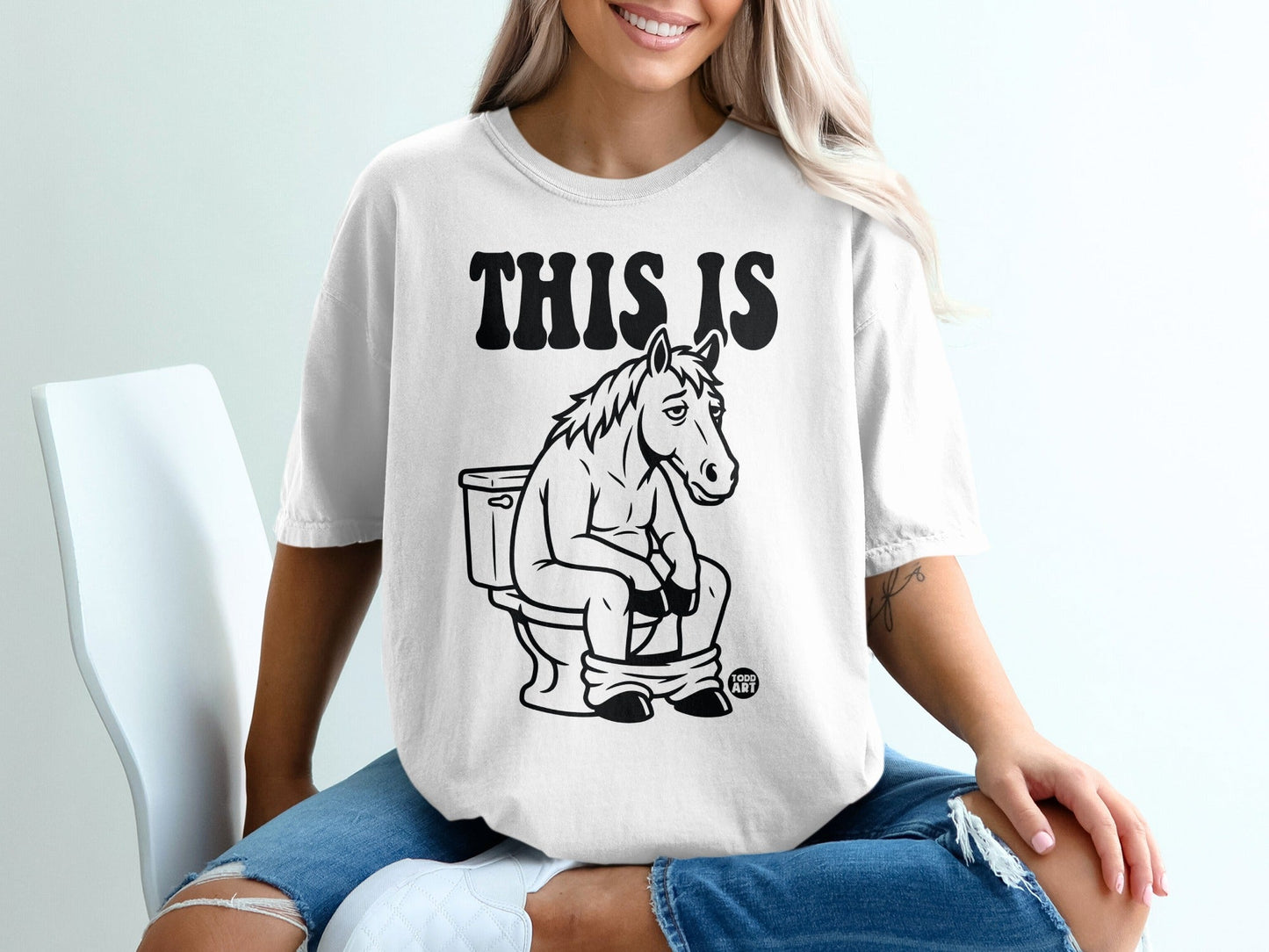 T-shirt graphic of a horse sitting on a toilet, with text "THIS IS".