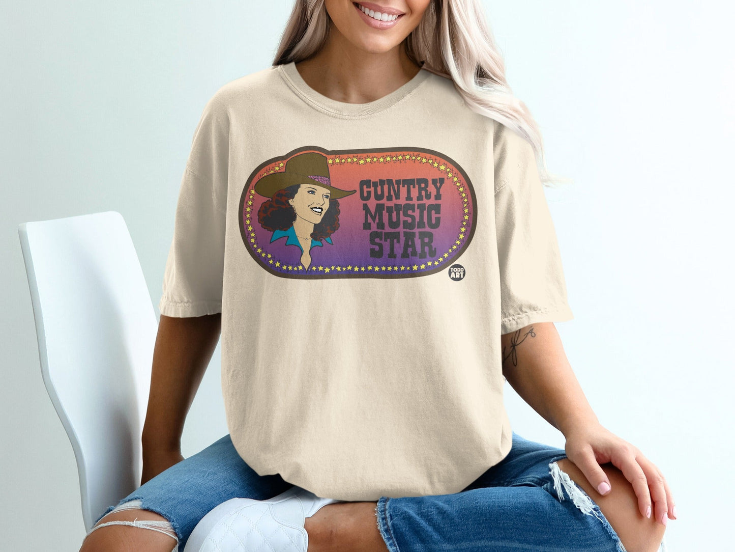 Cream t-shirt featuring a graphic of a woman with "Country Music Star" text.