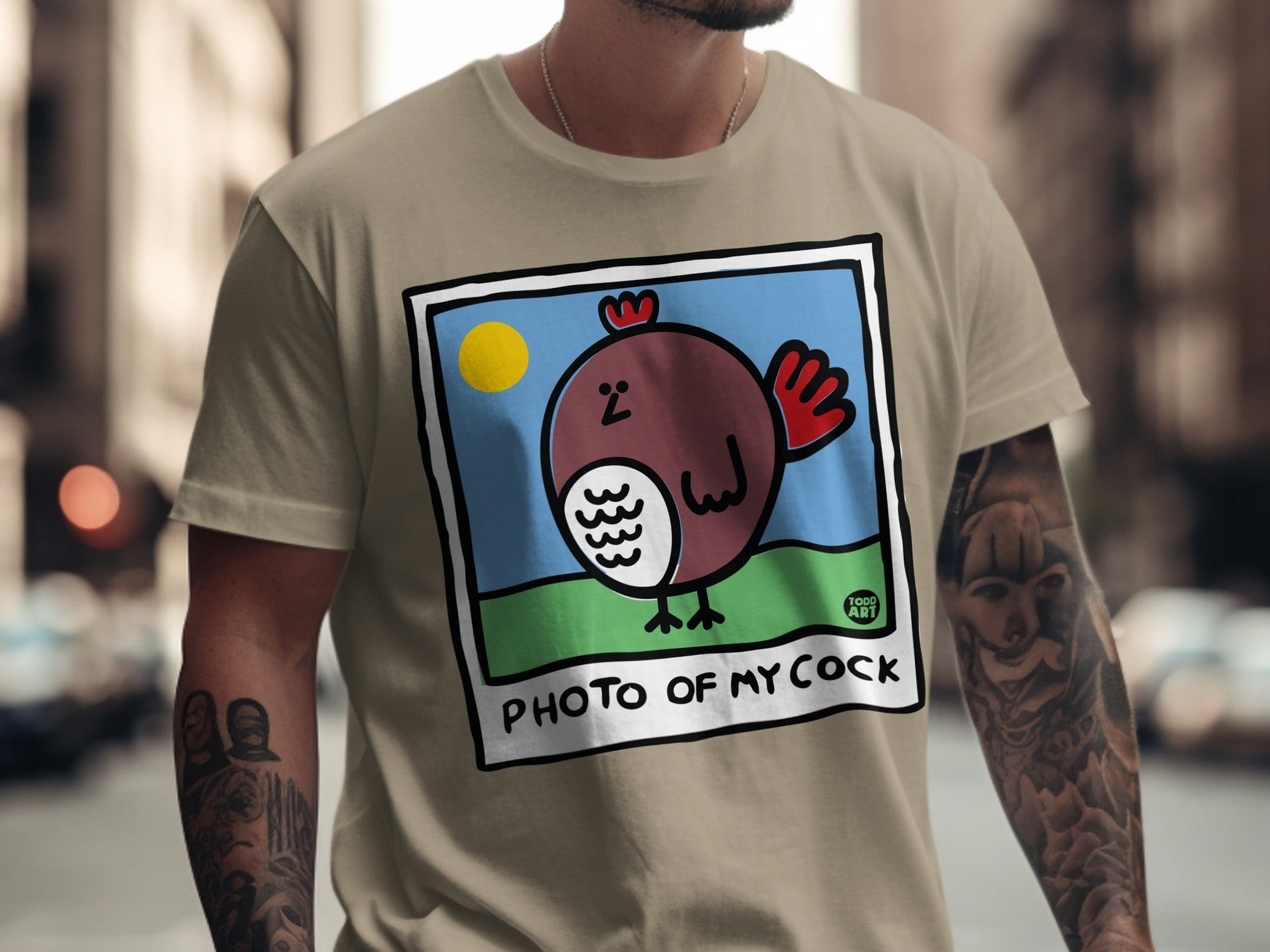 Brown cartoon chicken in a frame on a tan t-shirt.