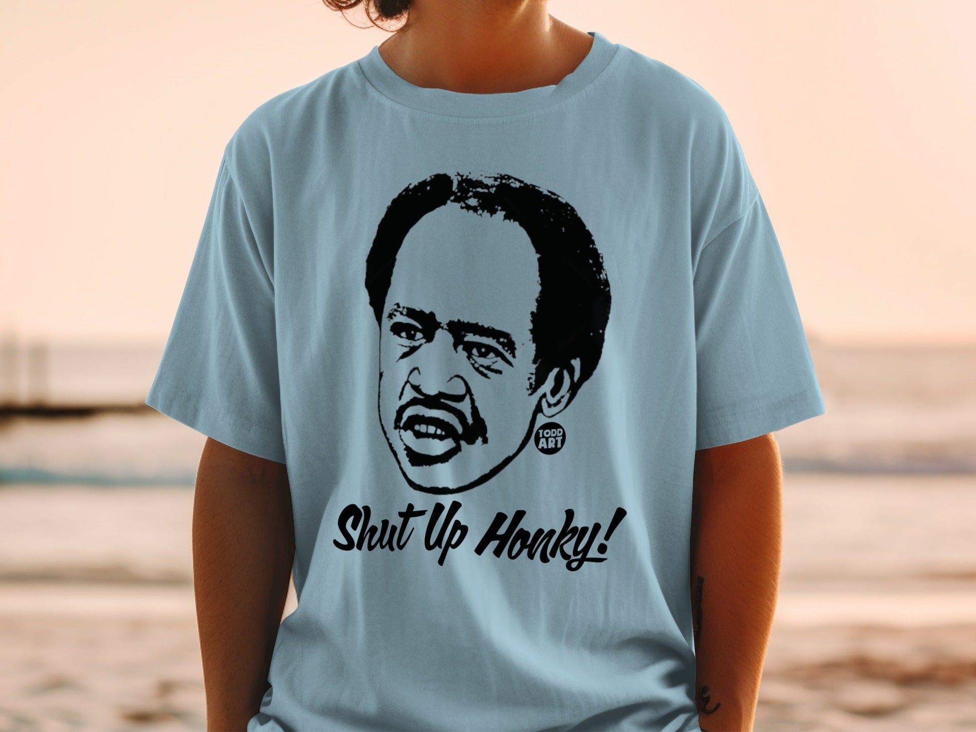 Light blue t-shirt with a black graphic of Redd Foxx saying "Shut Up Honky!".