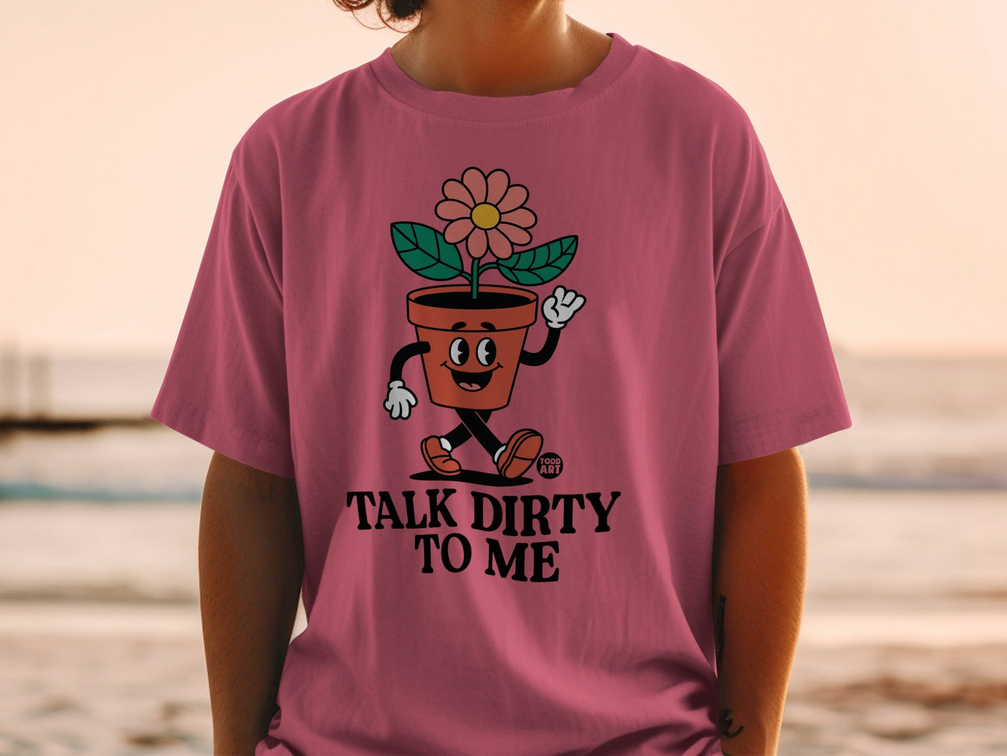 Pink t-shirt with a cartoon flower in a pot saying "Talk Dirty to Me."
