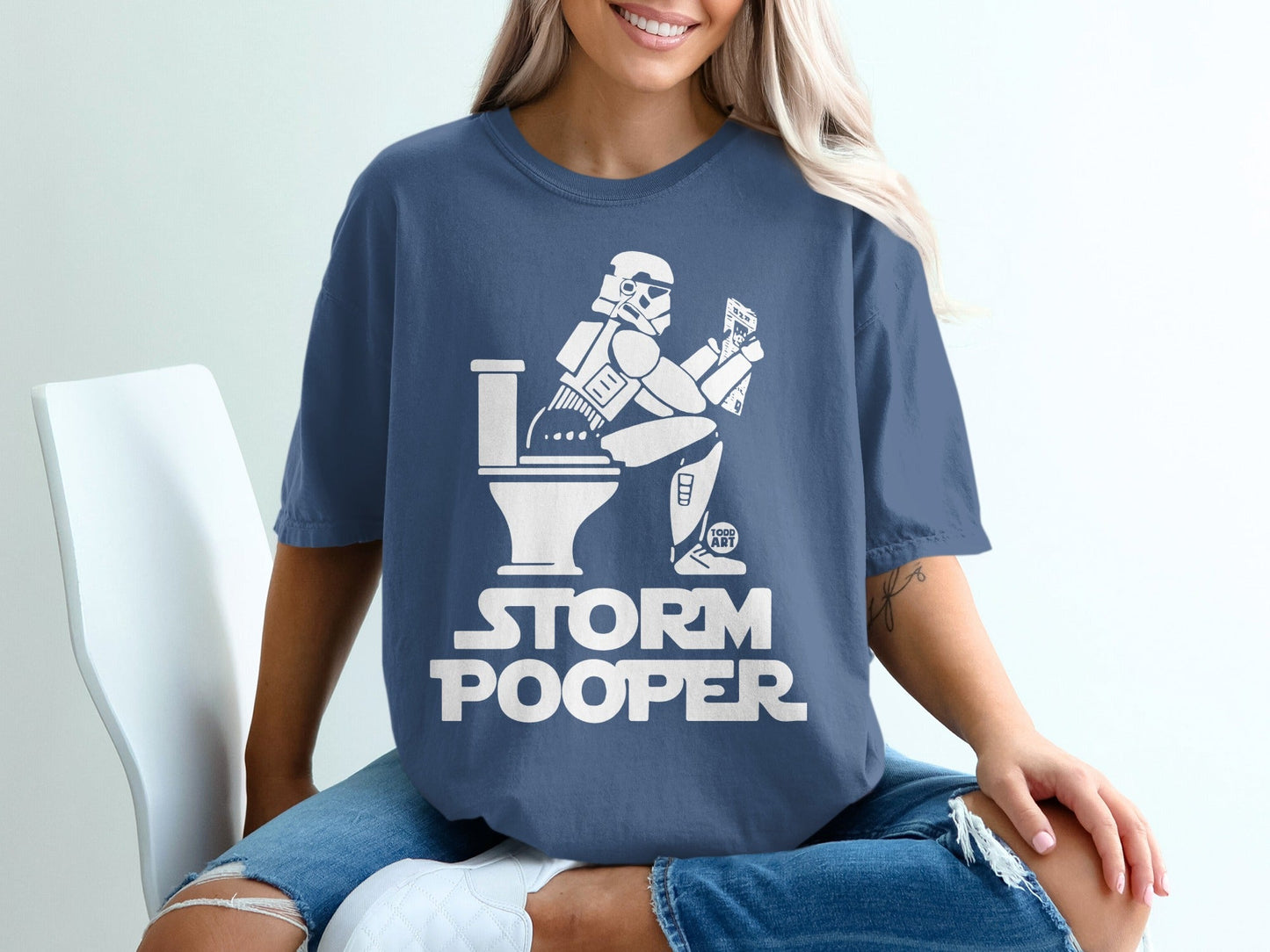 Stormtrooper sitting on a toilet, reading on a phone, text "STORM POOPER".