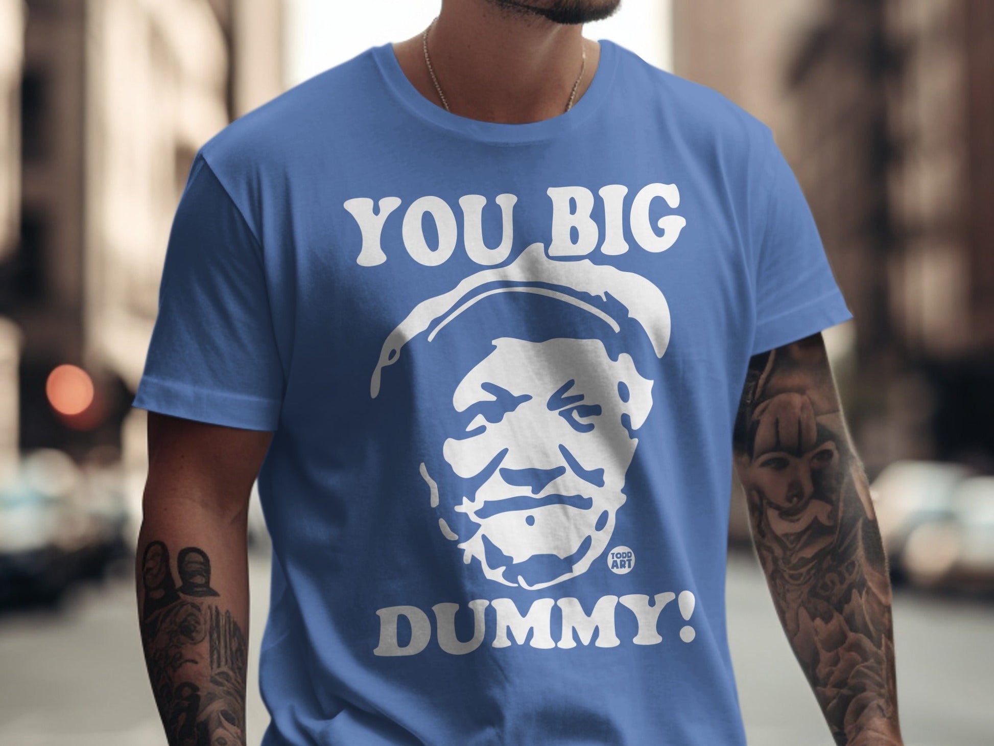 Blue t-shirt with white text and a portrait of a man saying "YOU BIG DUMMY!".