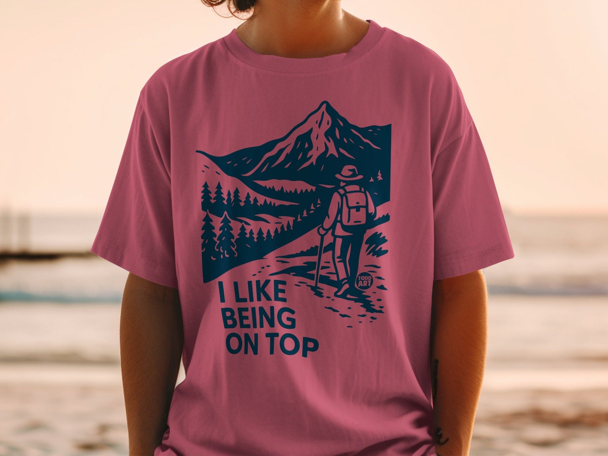 Pink t-shirt with "I Like Being On Top" text and mountain hiking graphic.