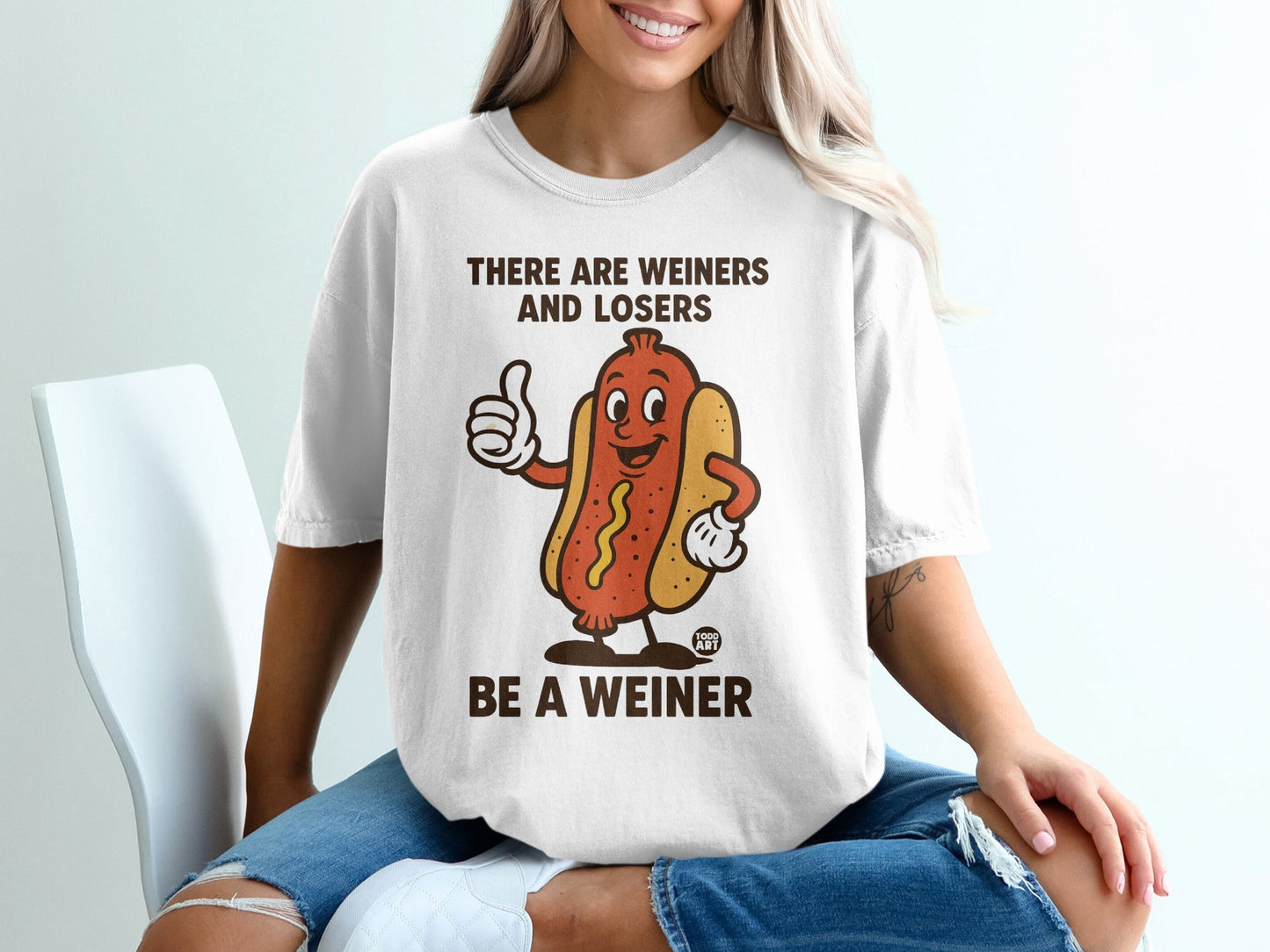 T-shirt with cartoon hot dog giving a thumbs up and text "BE A WEINER".