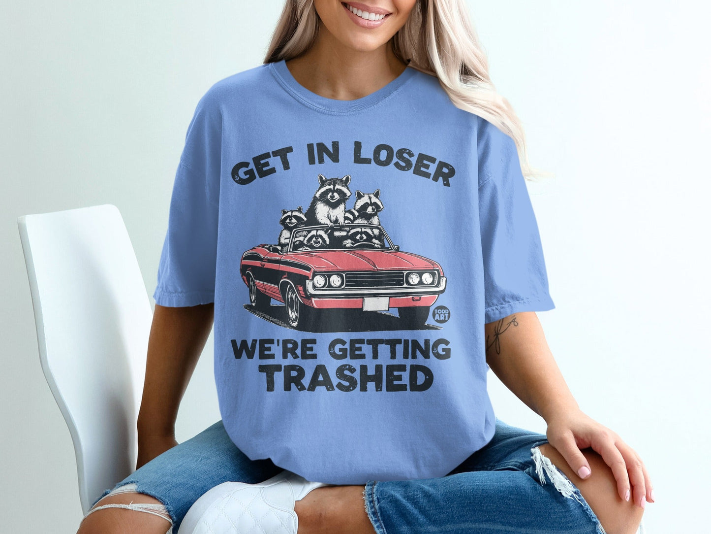 T-shirt with graphic of raccoons in a convertible, text reads "GET IN LOSER WE'RE GETTING TRASHED".