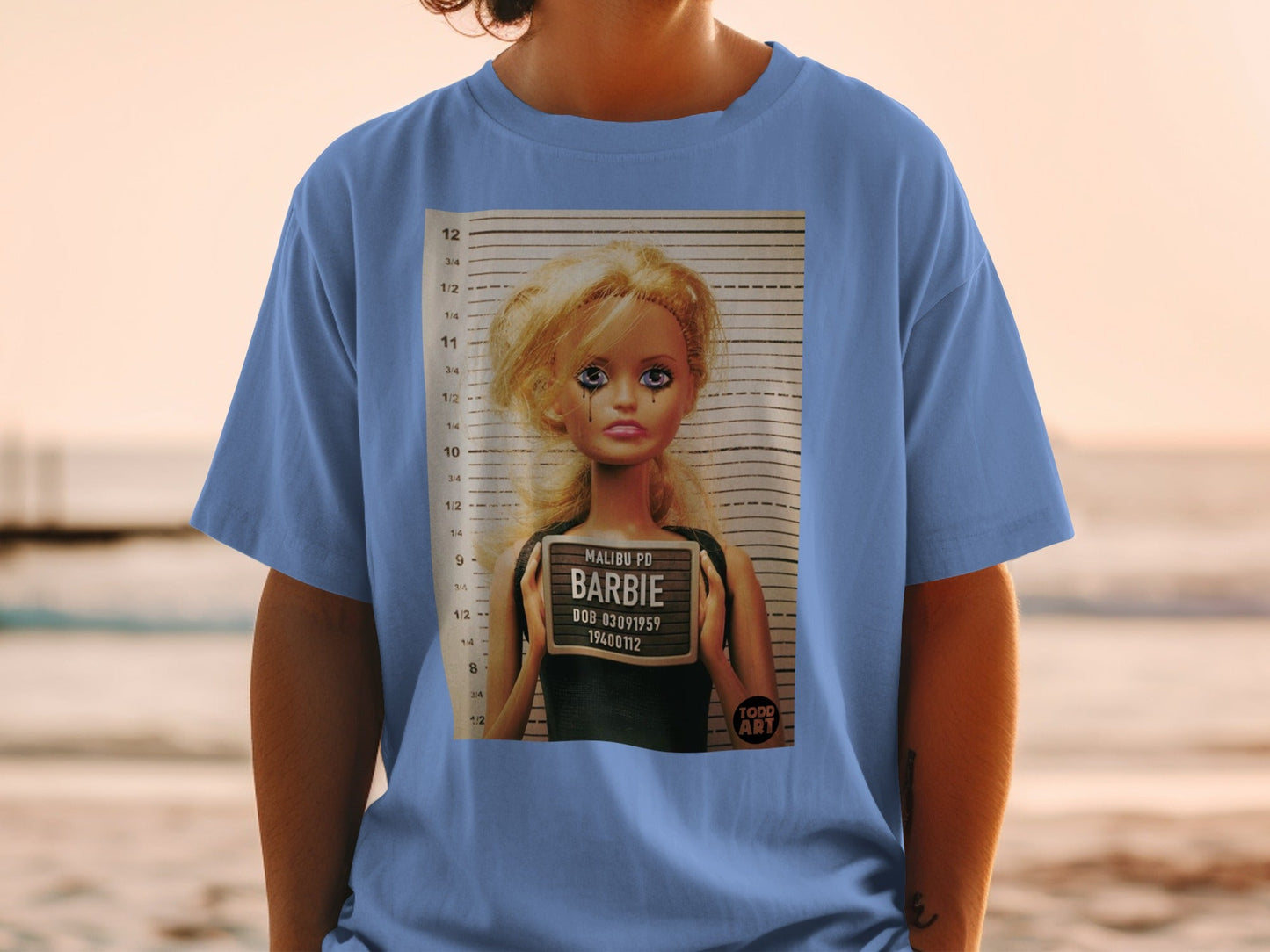 Barbie mugshot with "MALIBU PD" and birthdate on sign.