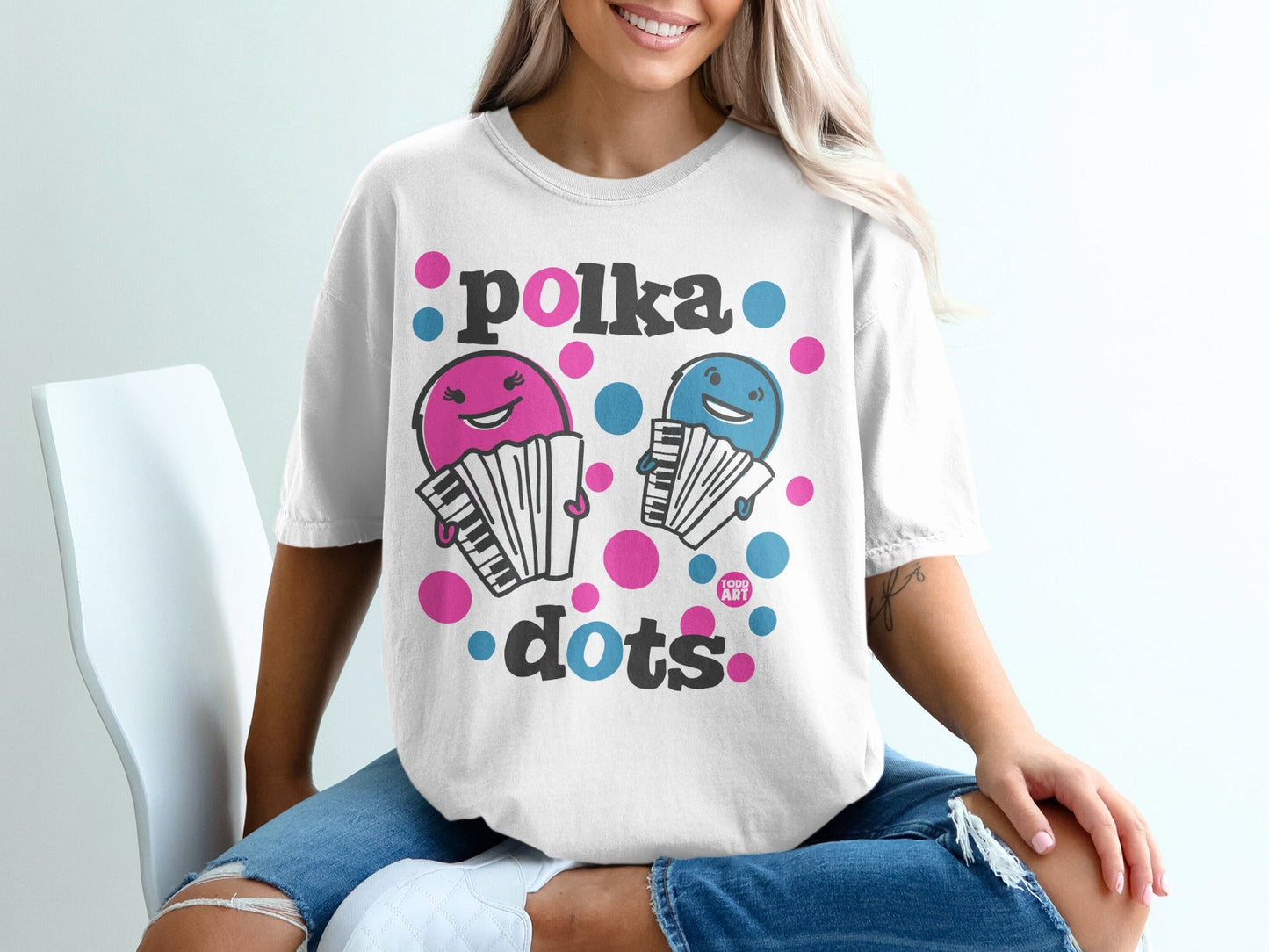 White t-shirt with "polka dots" text and cartoon figures playing accordions.