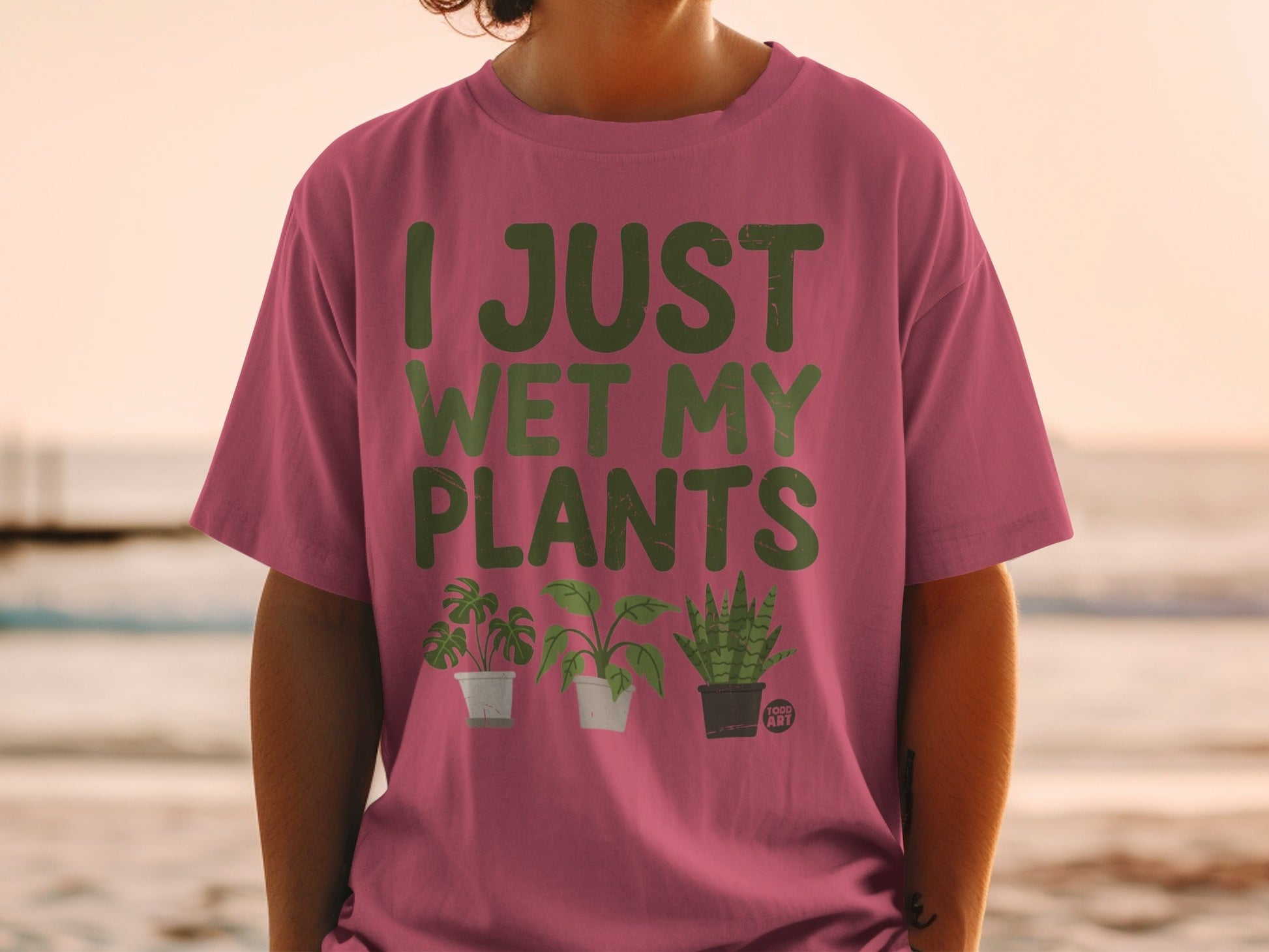 Pink t-shirt with "I JUST WET MY PLANTS" and three cartoon plants.