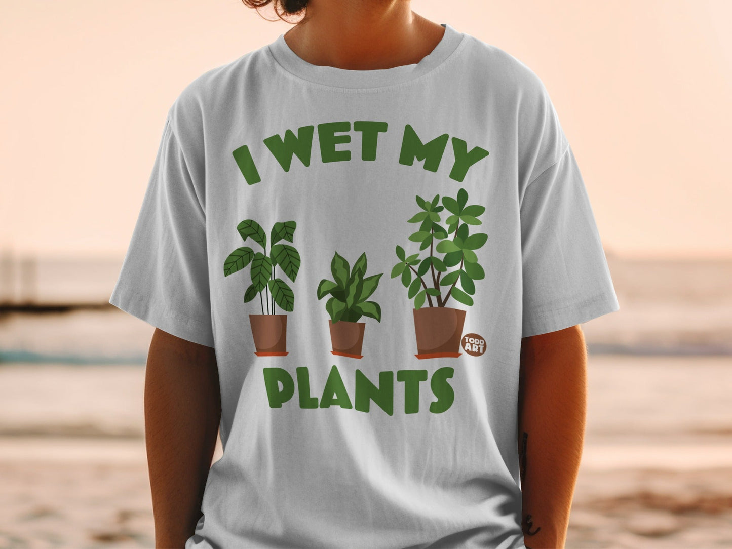 White t-shirt with "I WET MY PLANTS" and potted plants graphic.