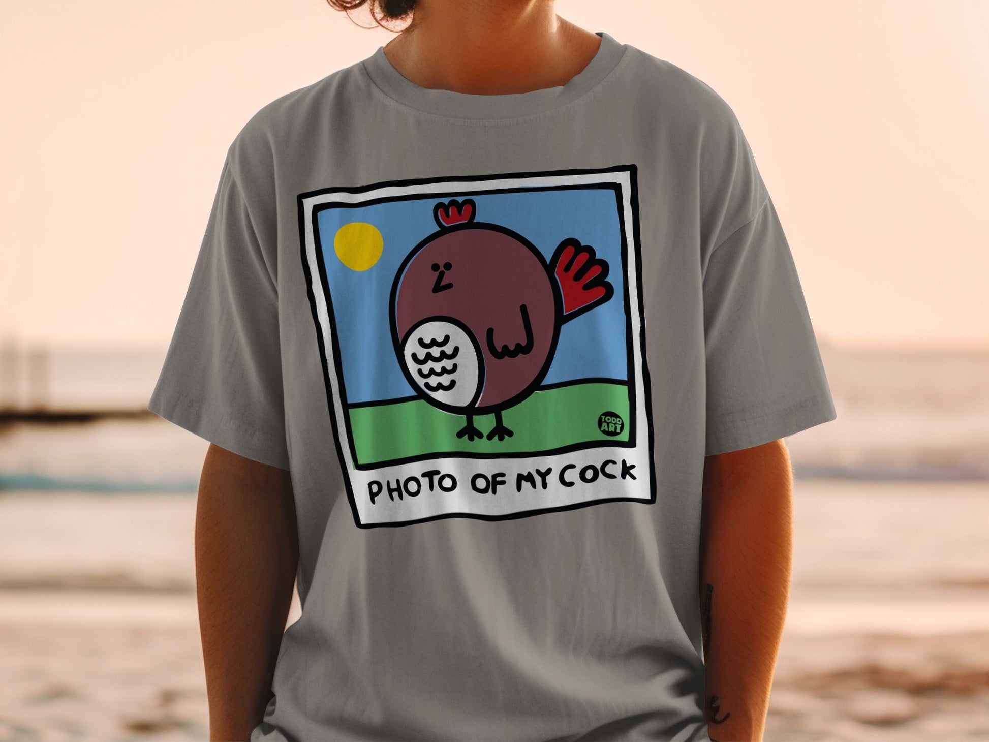 Gray t-shirt featuring a cartoon drawing of a rooster with "PHOTO OF MY COCK" text.