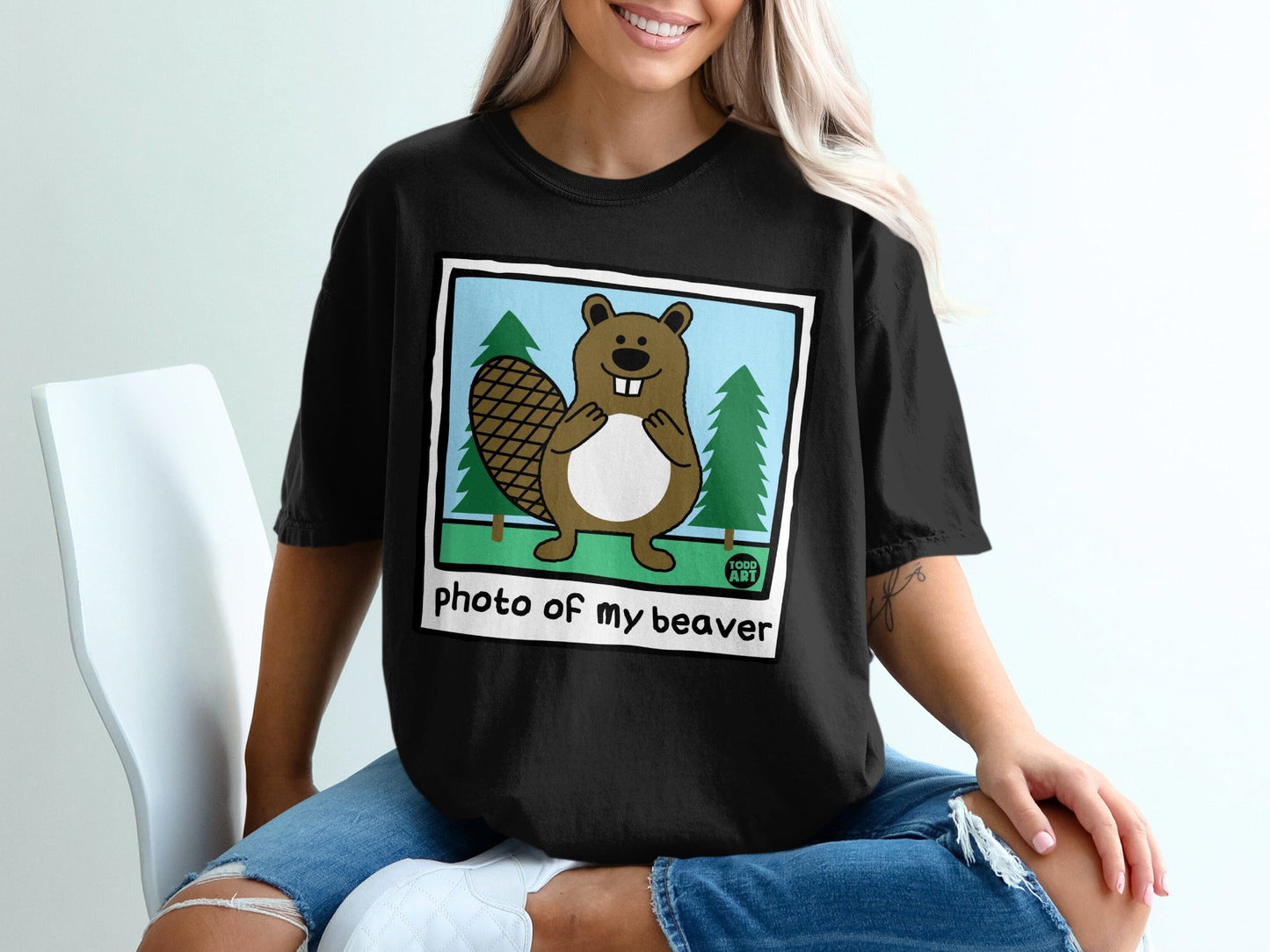 Illustration of a cartoon beaver in front of pine trees, text "Photo of my beaver".