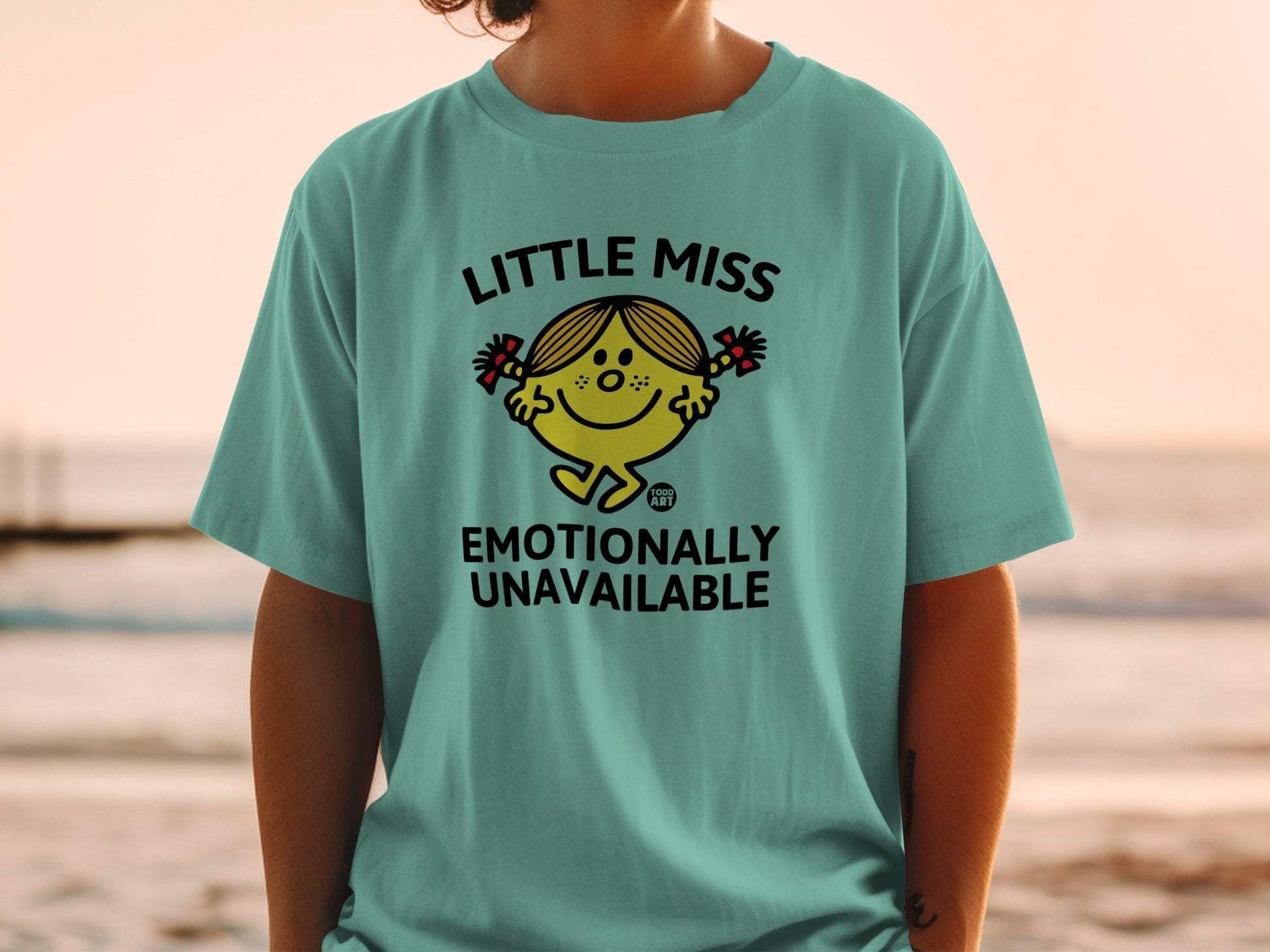 Teal t-shirt with Little Miss character saying "Emotionally Unavailable".