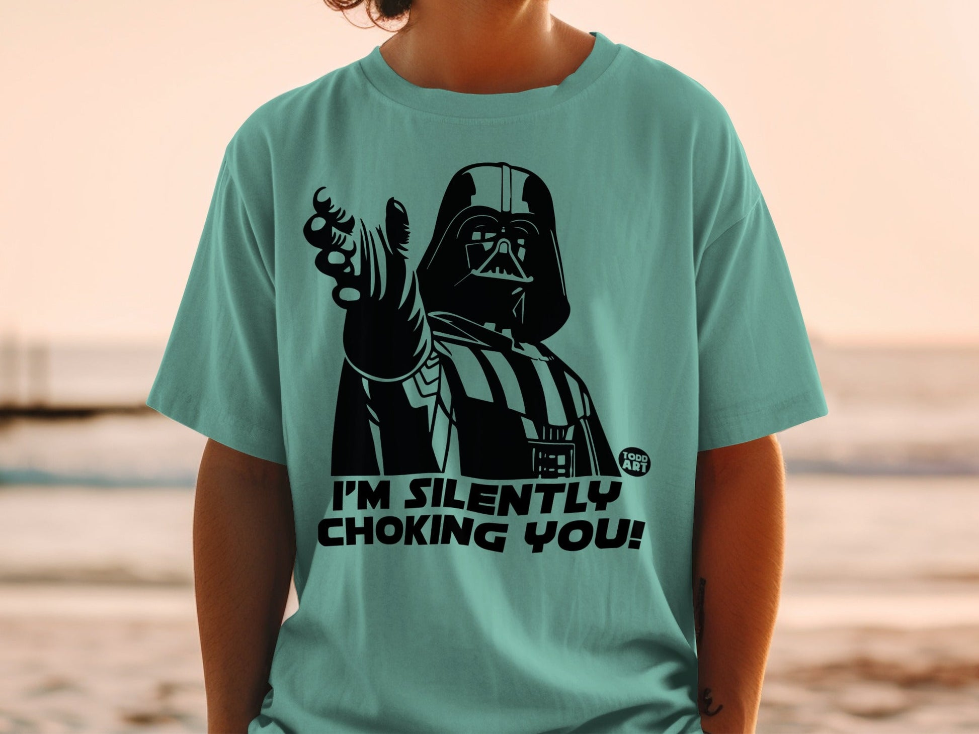 Darth Vader on a teal t-shirt says "I'M SILENTLY CHOKING YOU!".