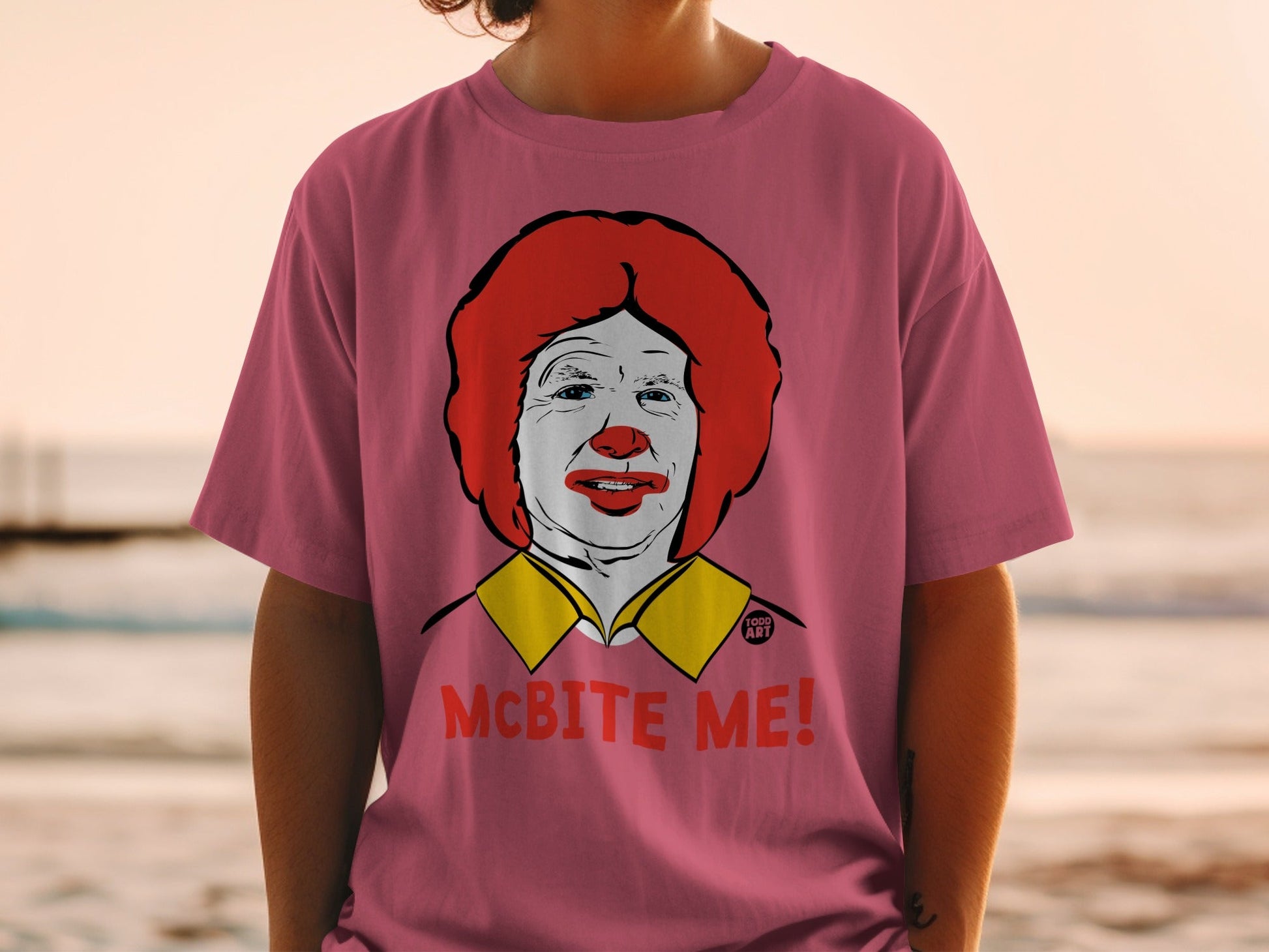 Pink t-shirt with a cartoon portrait of Ronald McDonald and "MCBITE ME!" text.