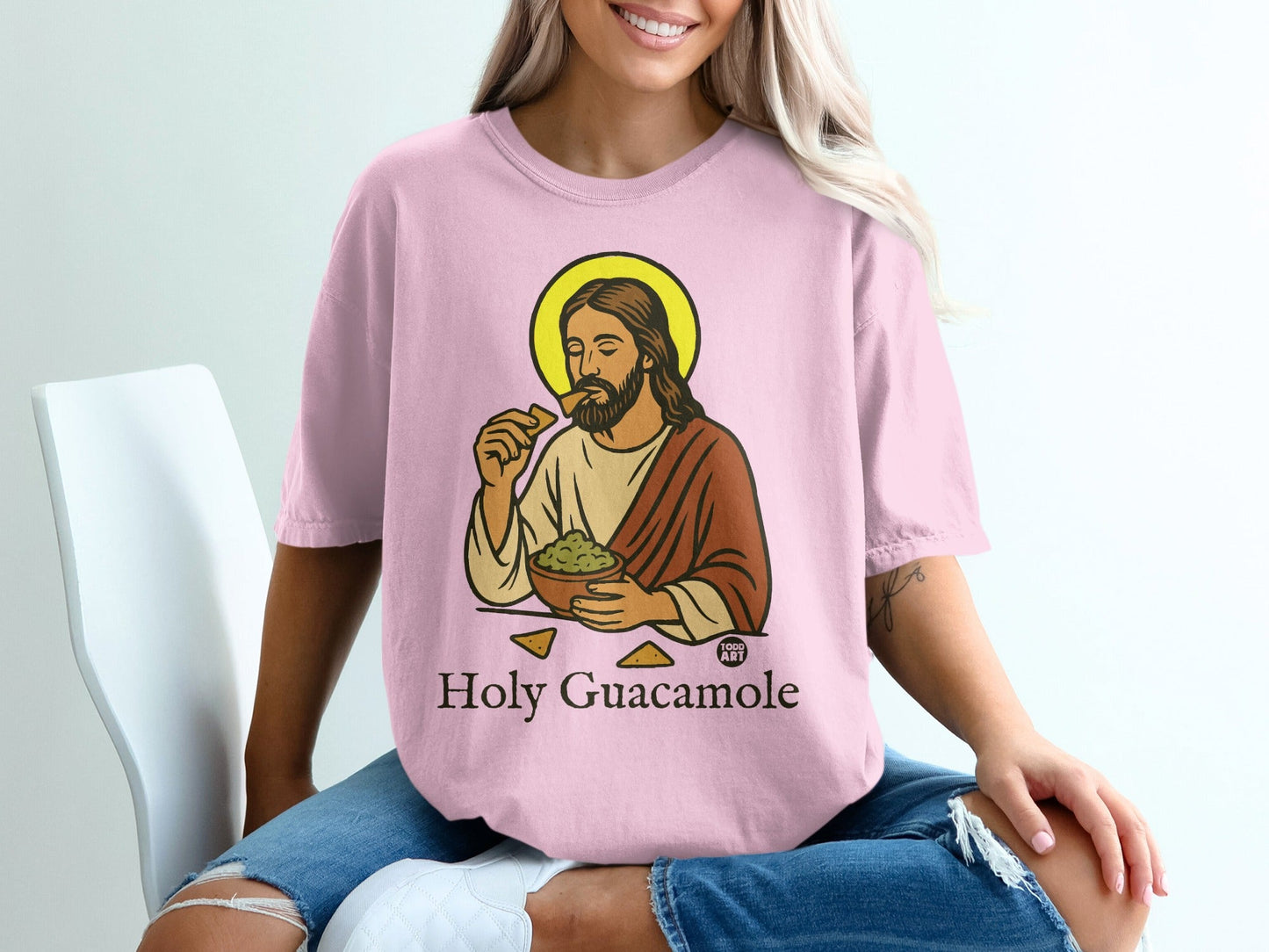Pink t-shirt with illustration of Jesus eating guacamole and chips, text "Holy Guacamole".