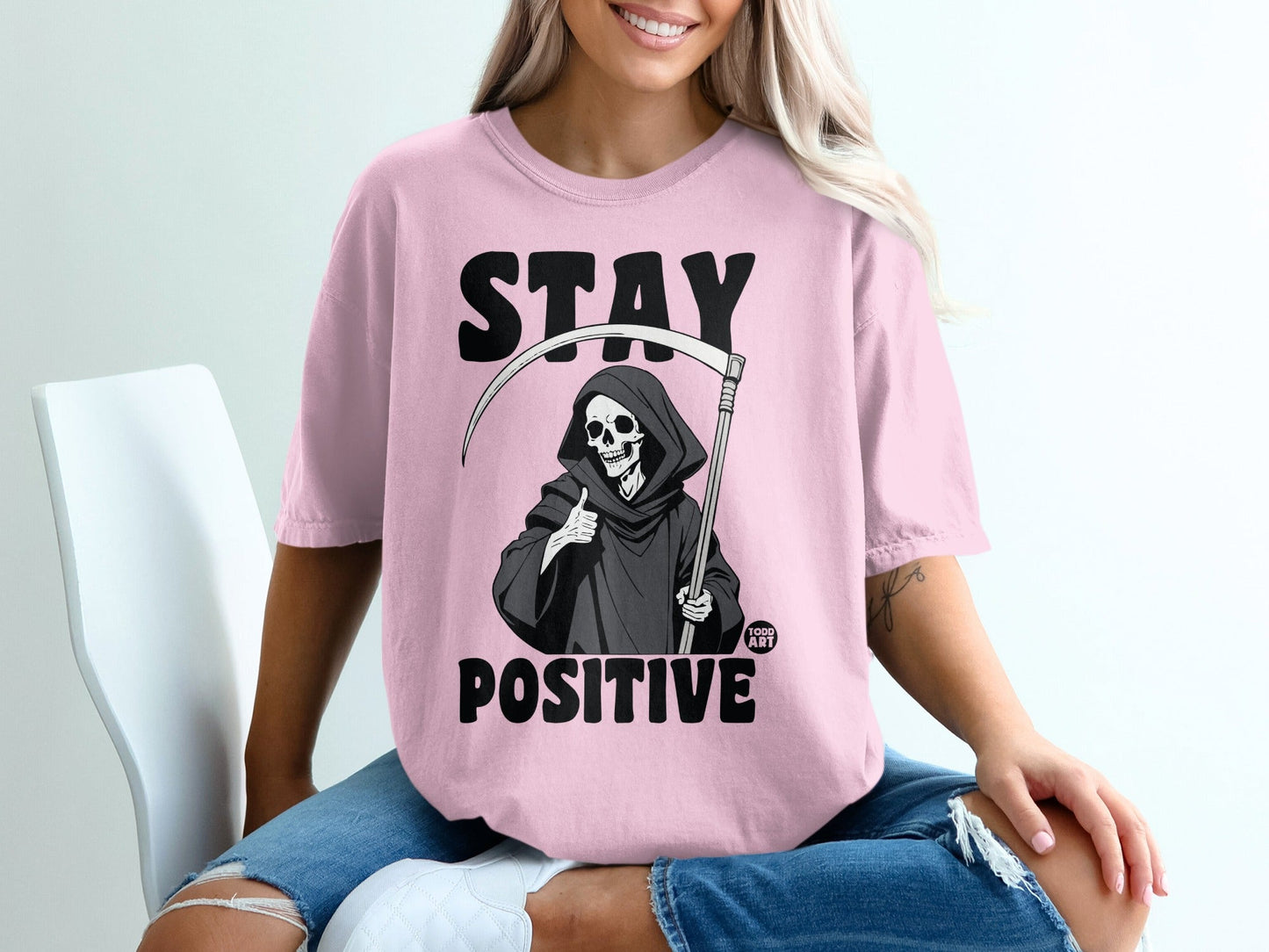 Pink t-shirt with "STAY POSITIVE" and Grim Reaper giving thumbs up.