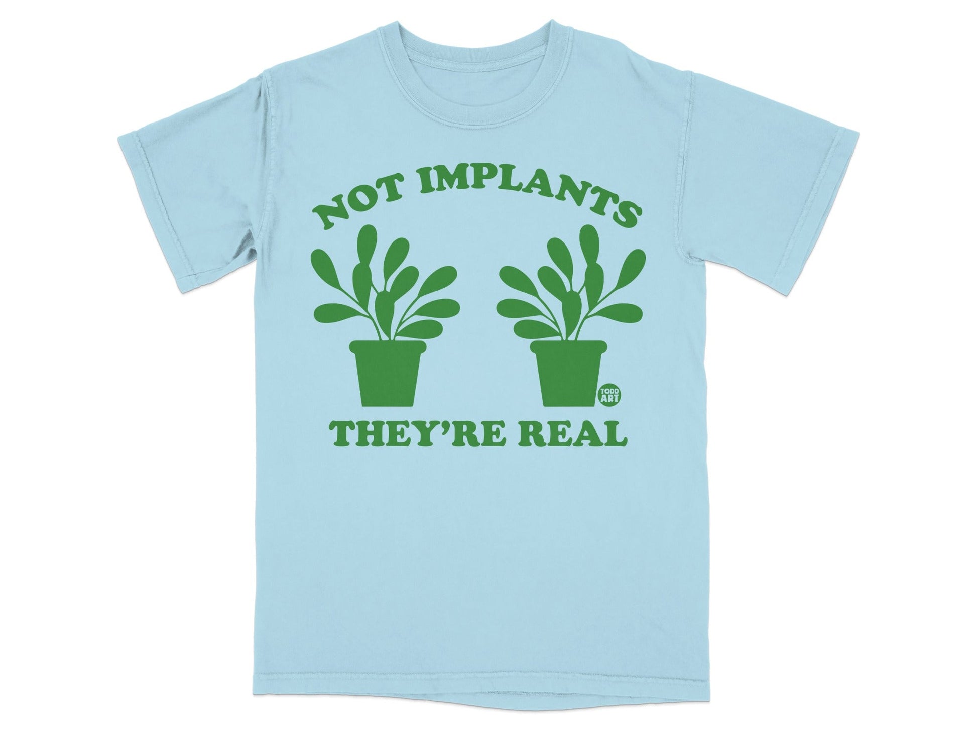 Light blue t-shirt with green text and potted plants reading "NOT IMPLANTS THEY'RE REAL".
