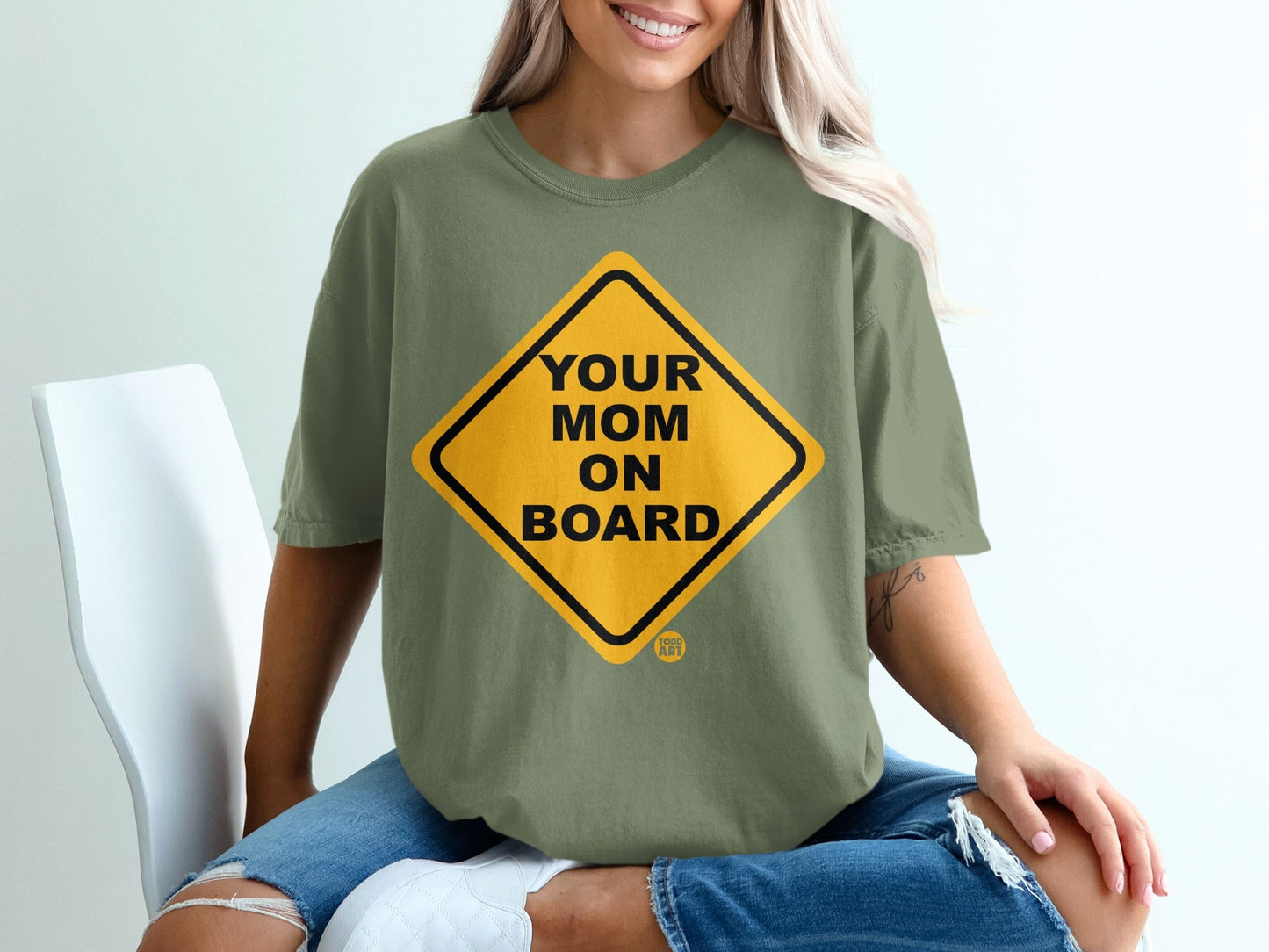 Yellow diamond sign graphic with "Your Mom On Board" text on olive green t-shirt.