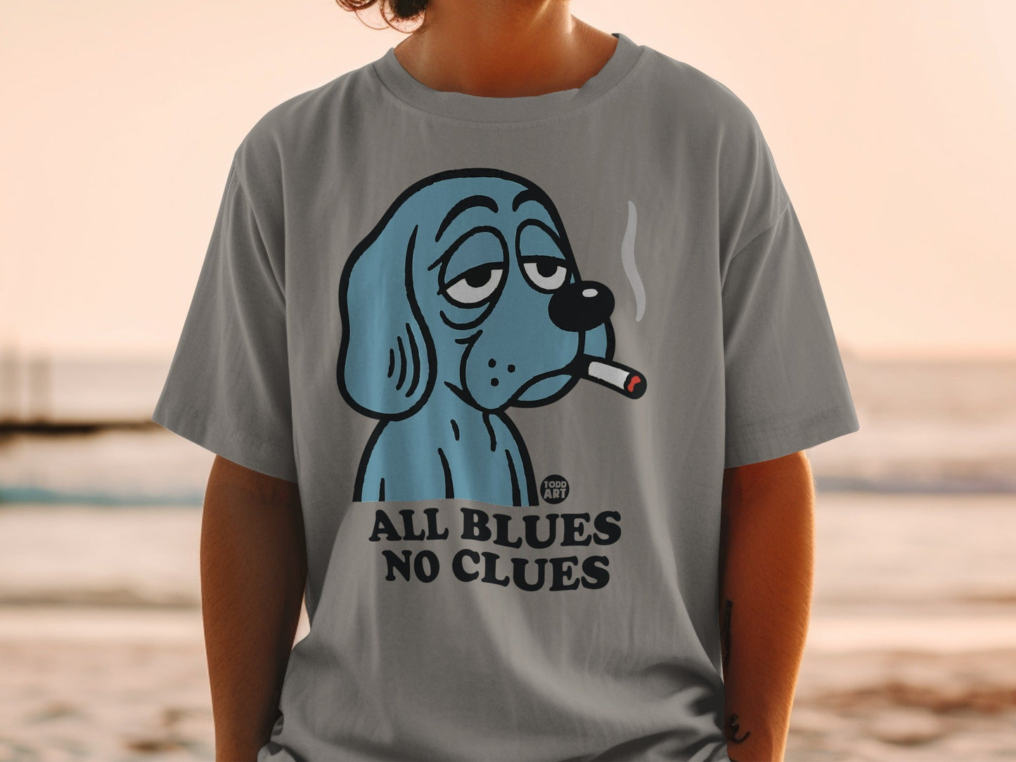 Gray t-shirt with a blue cartoon dog smoking a cigarette, text "ALL BLUES NO CLUES".