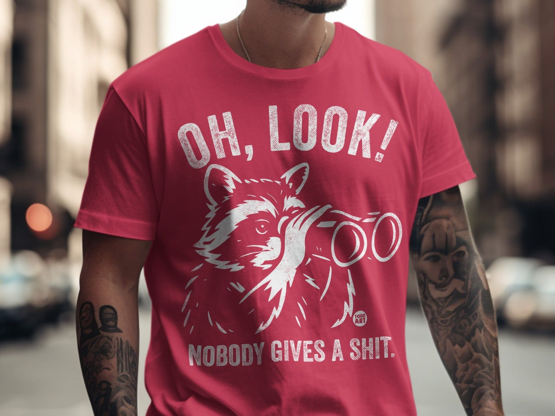 Red t-shirt with raccoon wearing binoculars and text "OH, LOOK! NOBODY GIVES A SHIT."