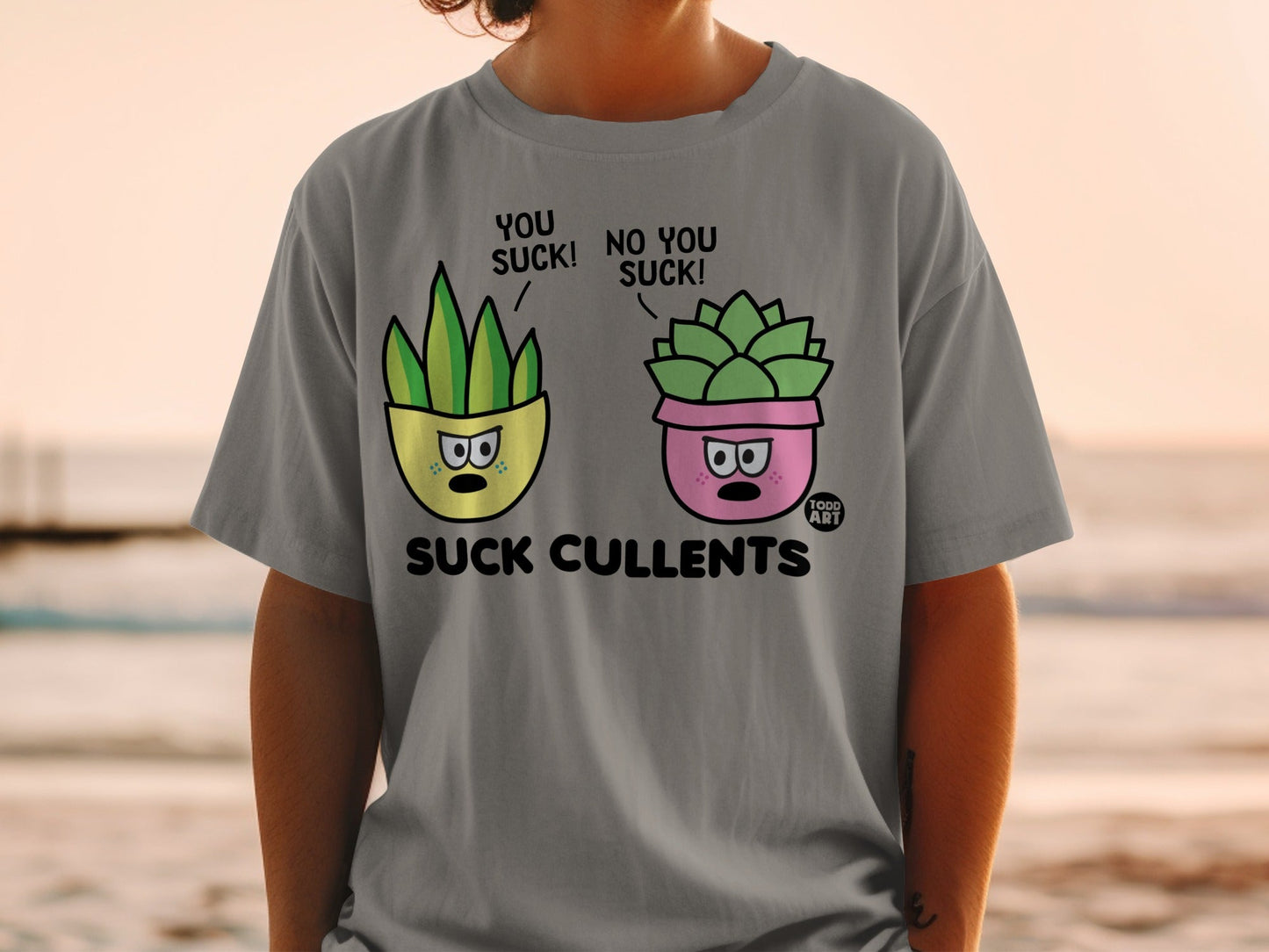 Gray t-shirt with graphic of two cartoon succulents in pots labeled "You suck!"